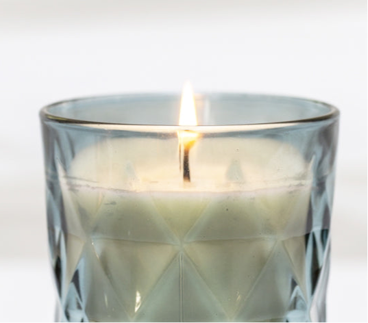 "Close-up of a fragrance-free candle in a chic blue glass holder, perfect for creating a relaxing ambiance without overpowering scents."