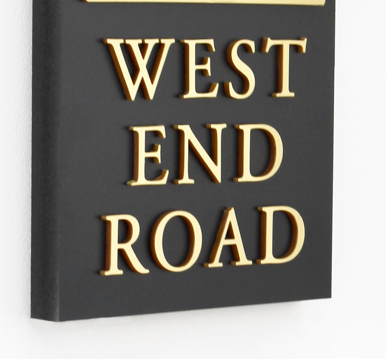 Elegant black outdoor house sign with raised gold lettering and a parallel dividing line, designed for narrow spaces. close up of raised design