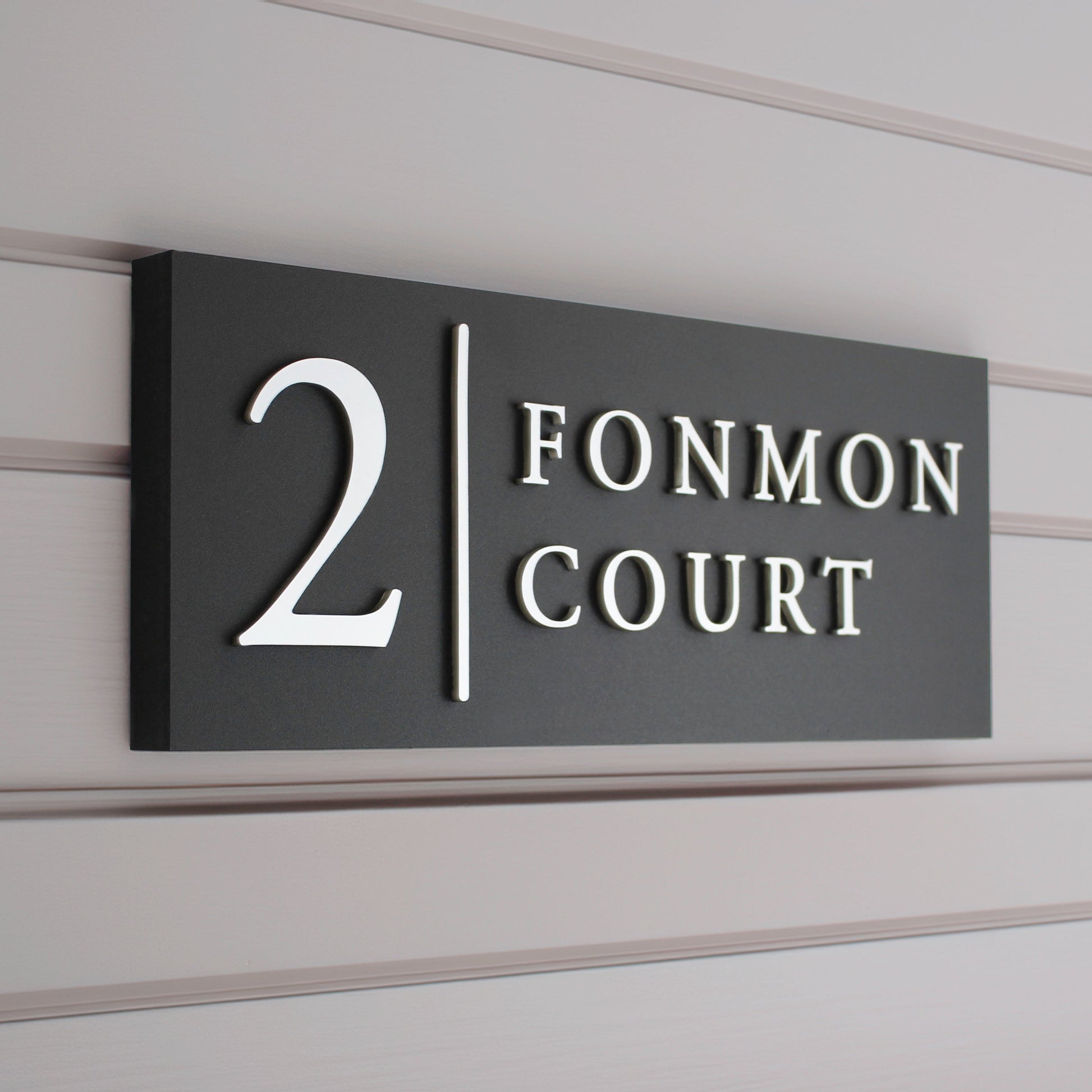 matte black house sign with raised silver design and vertical line