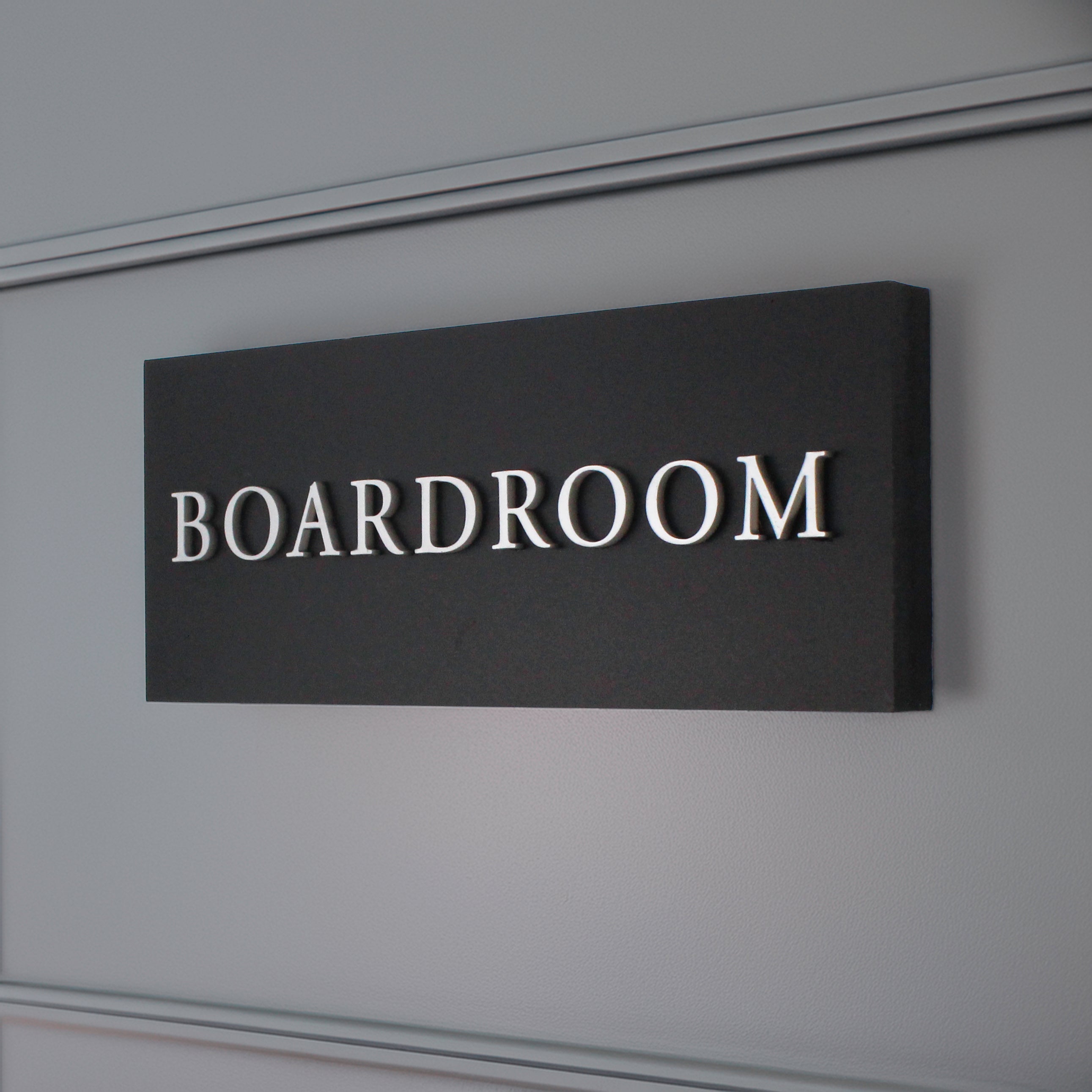 matte black sign with raised silver design in an internal office space