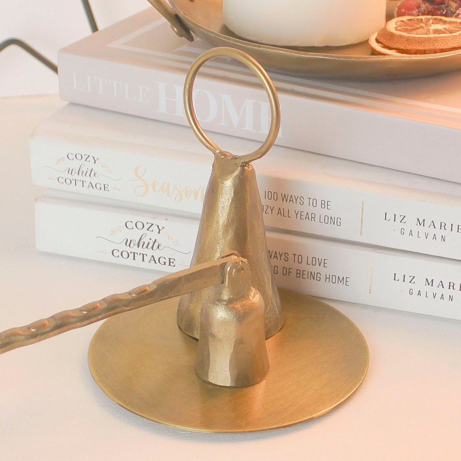 "Elegant artisan hand-forged brass snuffer, designed in the shape of a cow bell, perfect for adding a unique and weighty touch to your candle décor." styled with our long arm brass snuffer