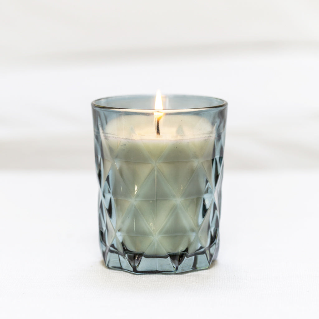 "Elegant blue glass fragrance-free candle, offering a soothing glow for any room with its stylish and simple design."