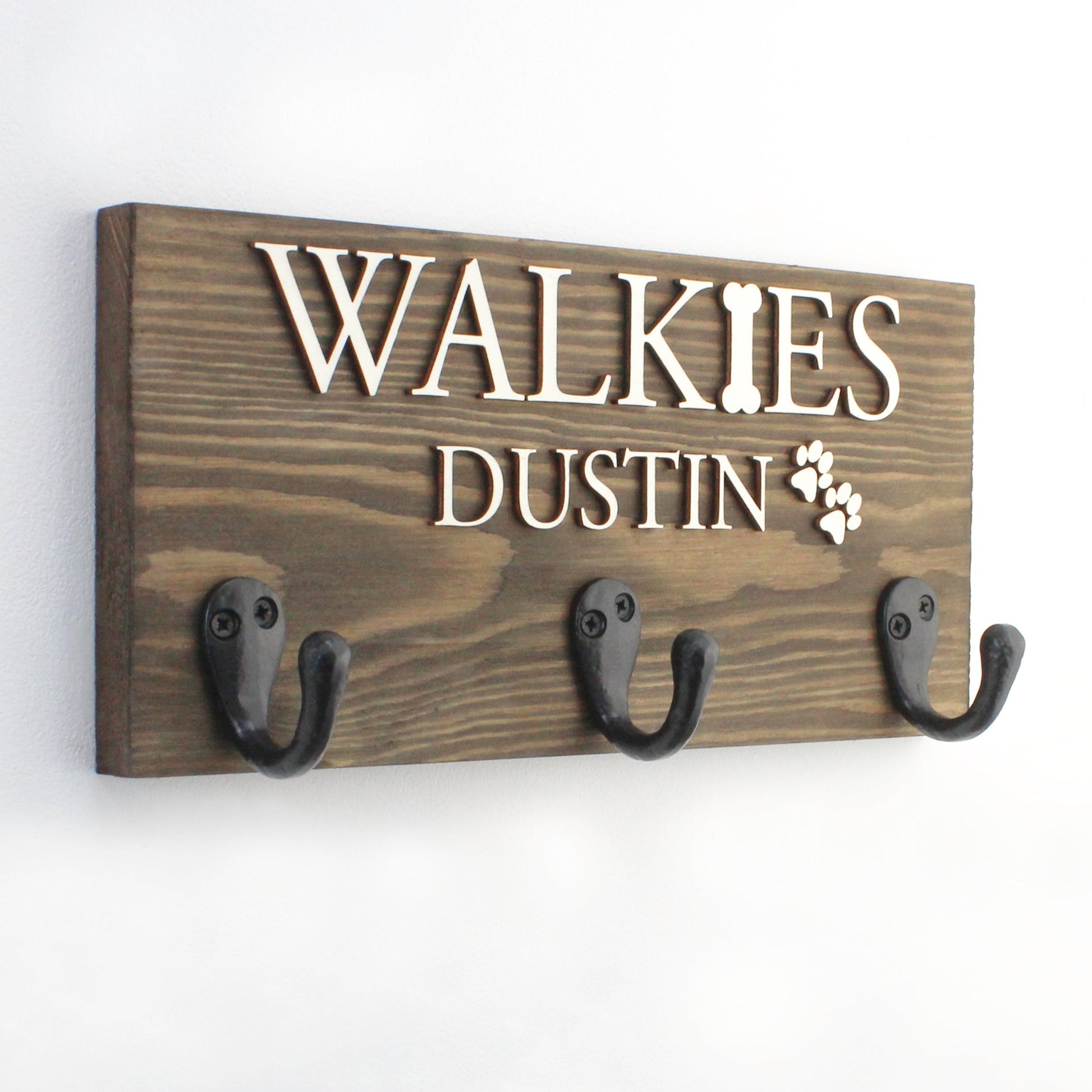 This personalised dog lead hook in a classic English oak finish brings timeless elegance to your pet’s space. Handcrafted from premium wood, it features raised lettering in natural wood or black, perfect for showcasing your pet’s name. Add a paw print for an extra personal touch, making it a charming and functional storage solution for your pet’s leads, collars, and accessories.