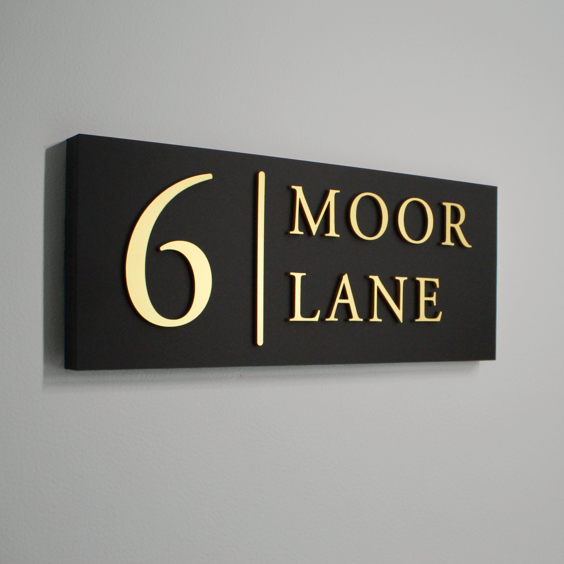 Black sign with gold raised design with vertical line