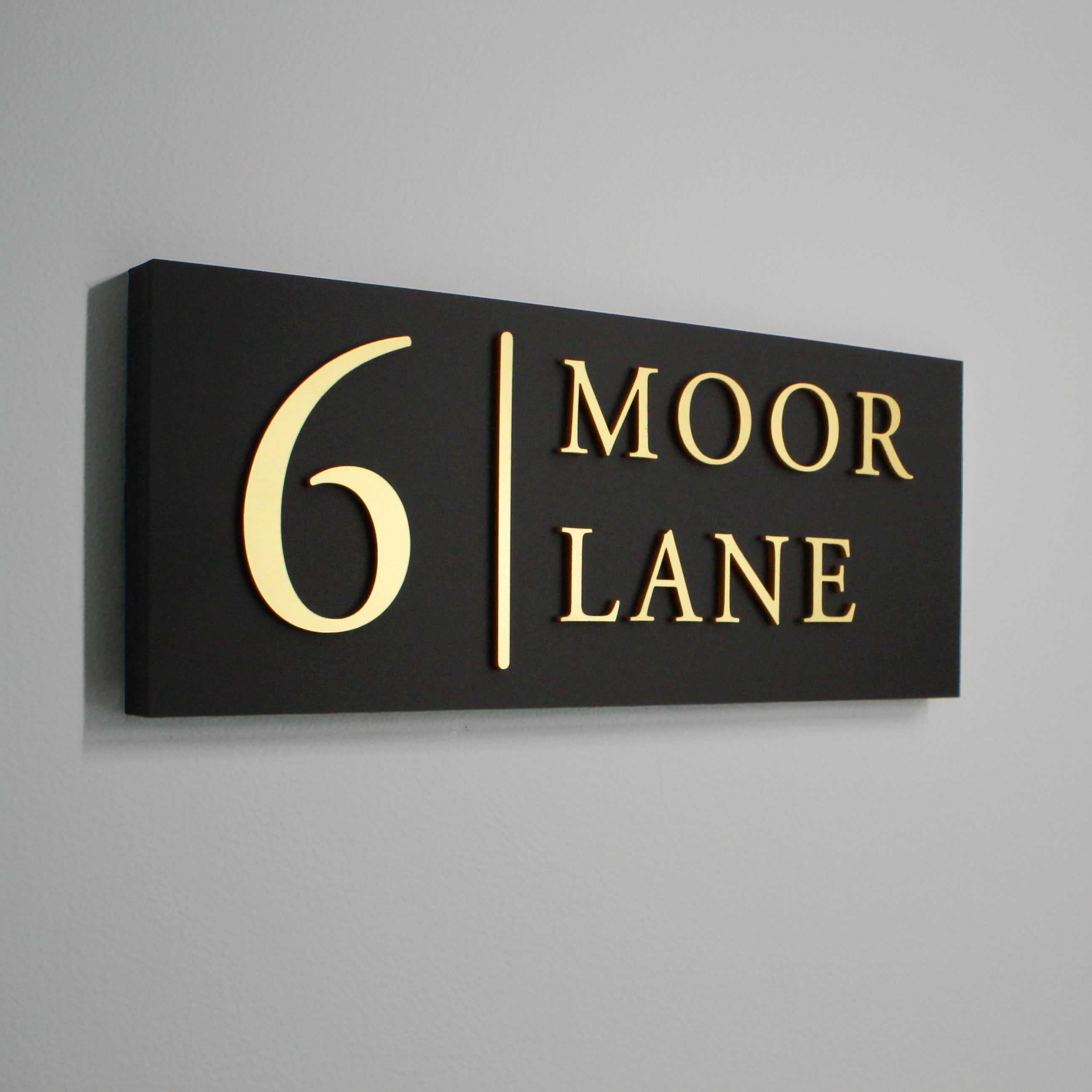 Black sign with gold raised design with vertical line