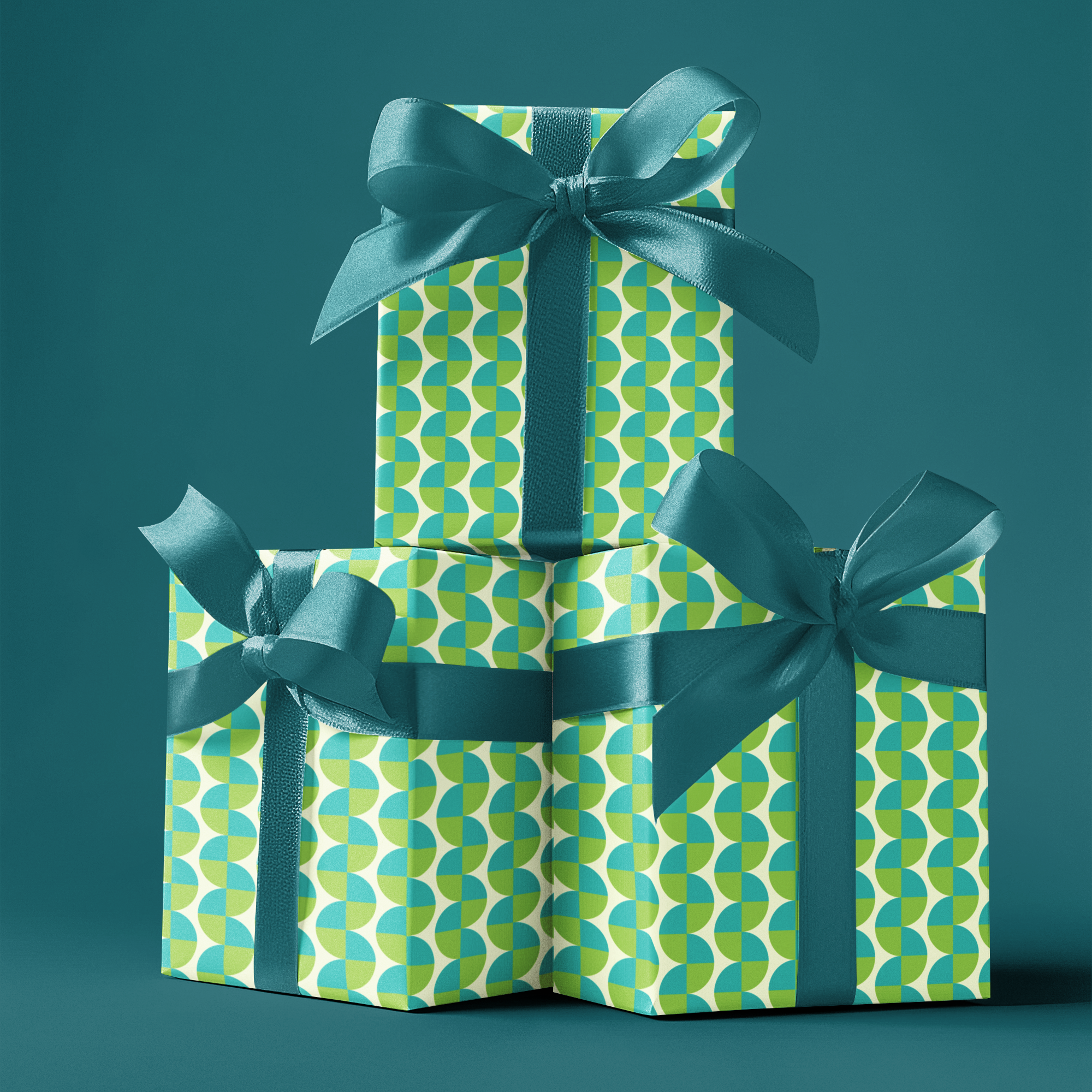 Three stacked gift boxes with green and blue patterned wrapping paper and ribbons on a teal background