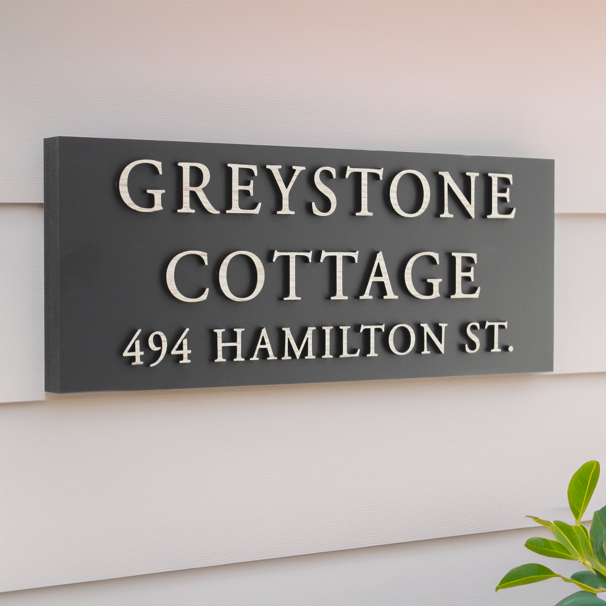 House sign rectangular shape in matte black with raised wood effect design wording over 3 lines 