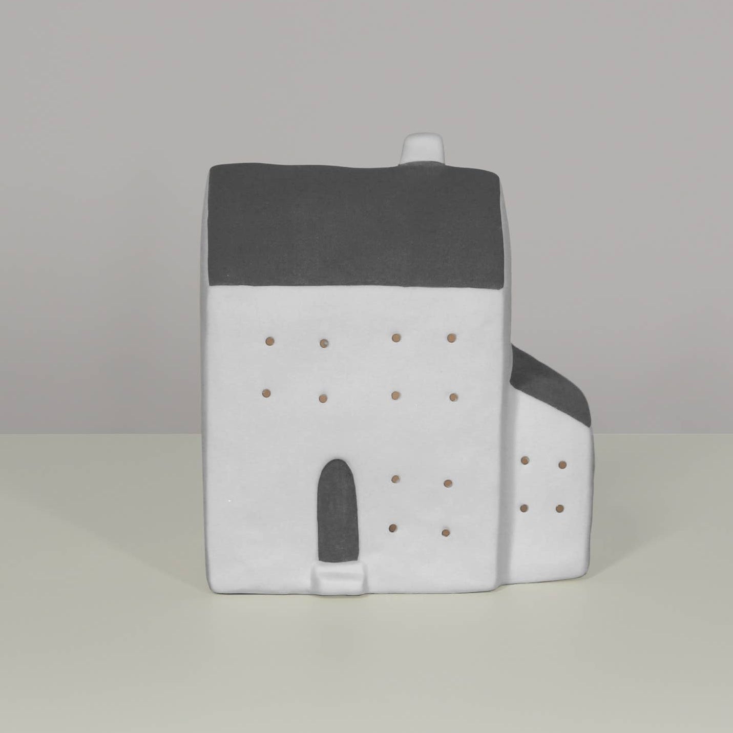 Small model of a house with a gray roof on a light gray background