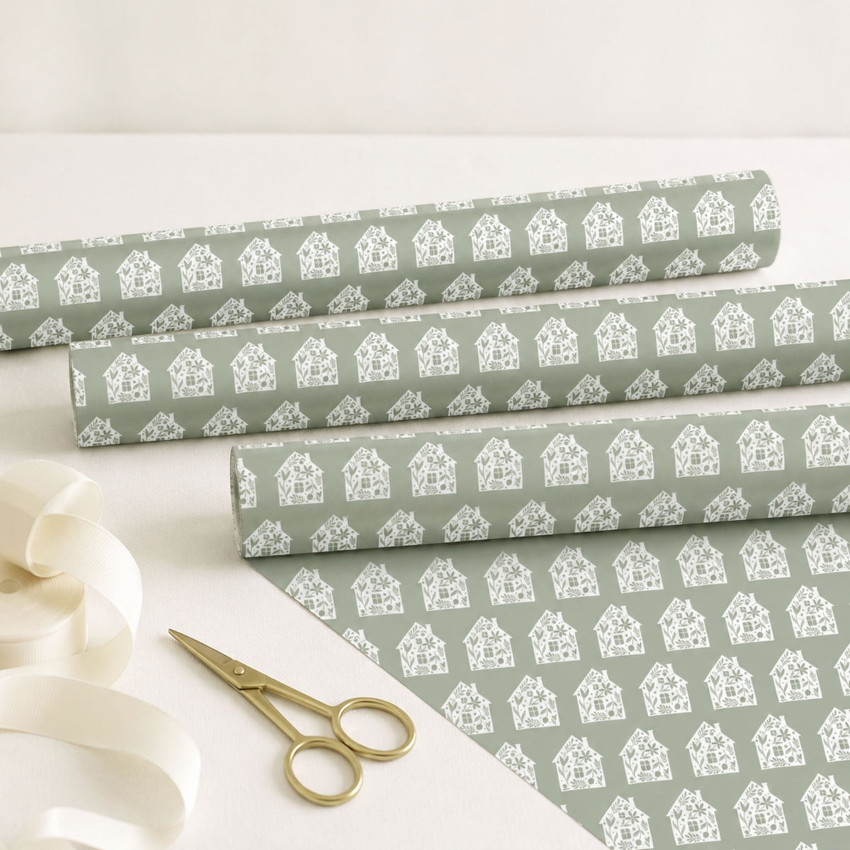 Rolls of sage New Home wrapping paper with scissors and ribbon