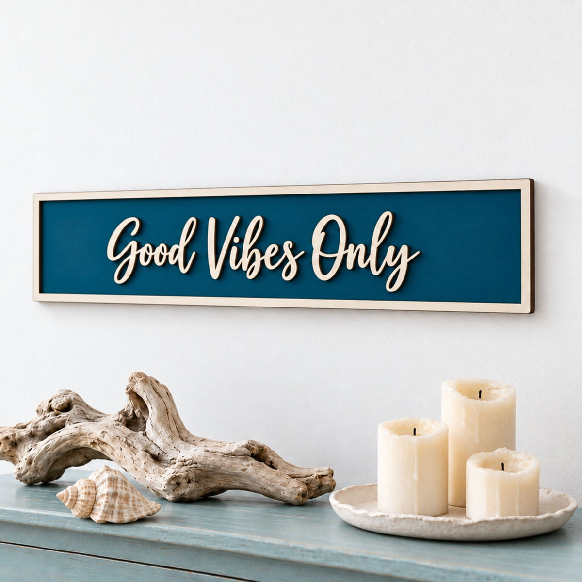 Peacock blue “Good Vibes Only” wooden sign with raised script lettering, styled with driftwood and candles.