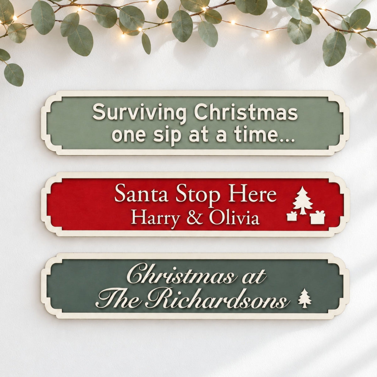 Three personalised Christmas signs in green and red, showing festive quotes, children’s names and a family name.
