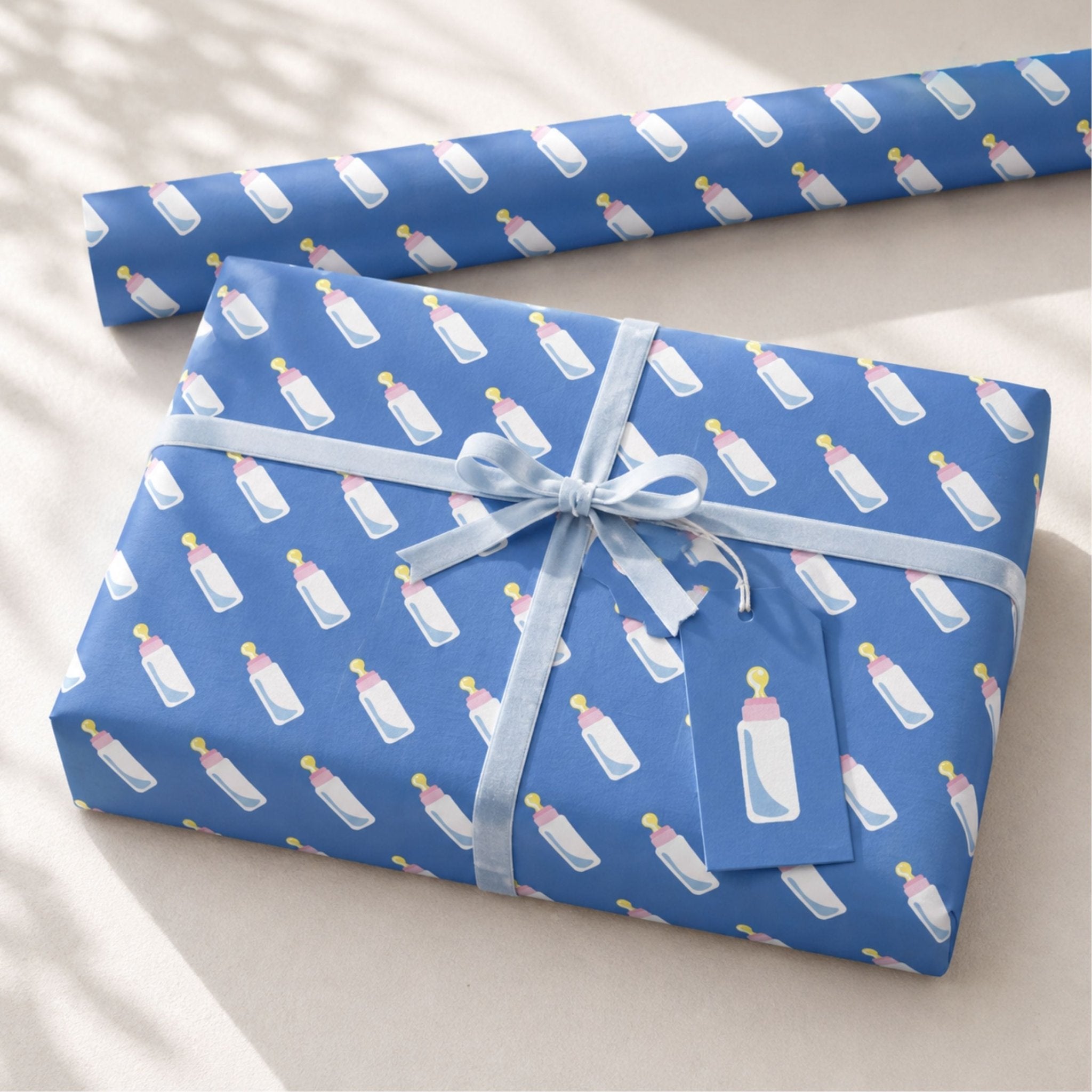Blue baby bottle gift wrapping paper with matching gift tag and ribbon