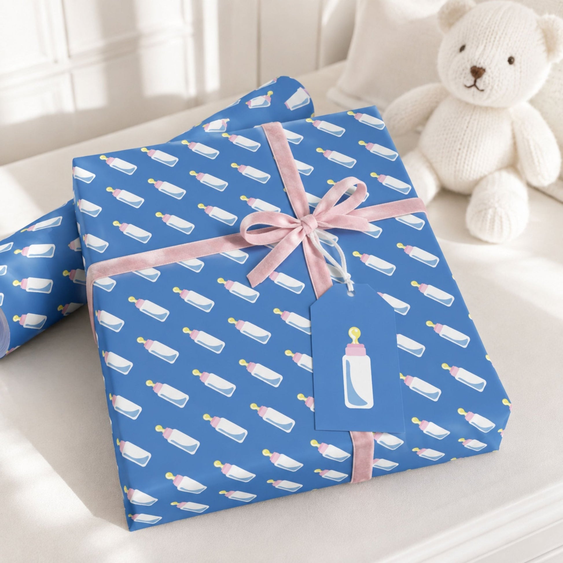 Blue baby bottle wrapping paper styled with pink ribbon for a new baby gift