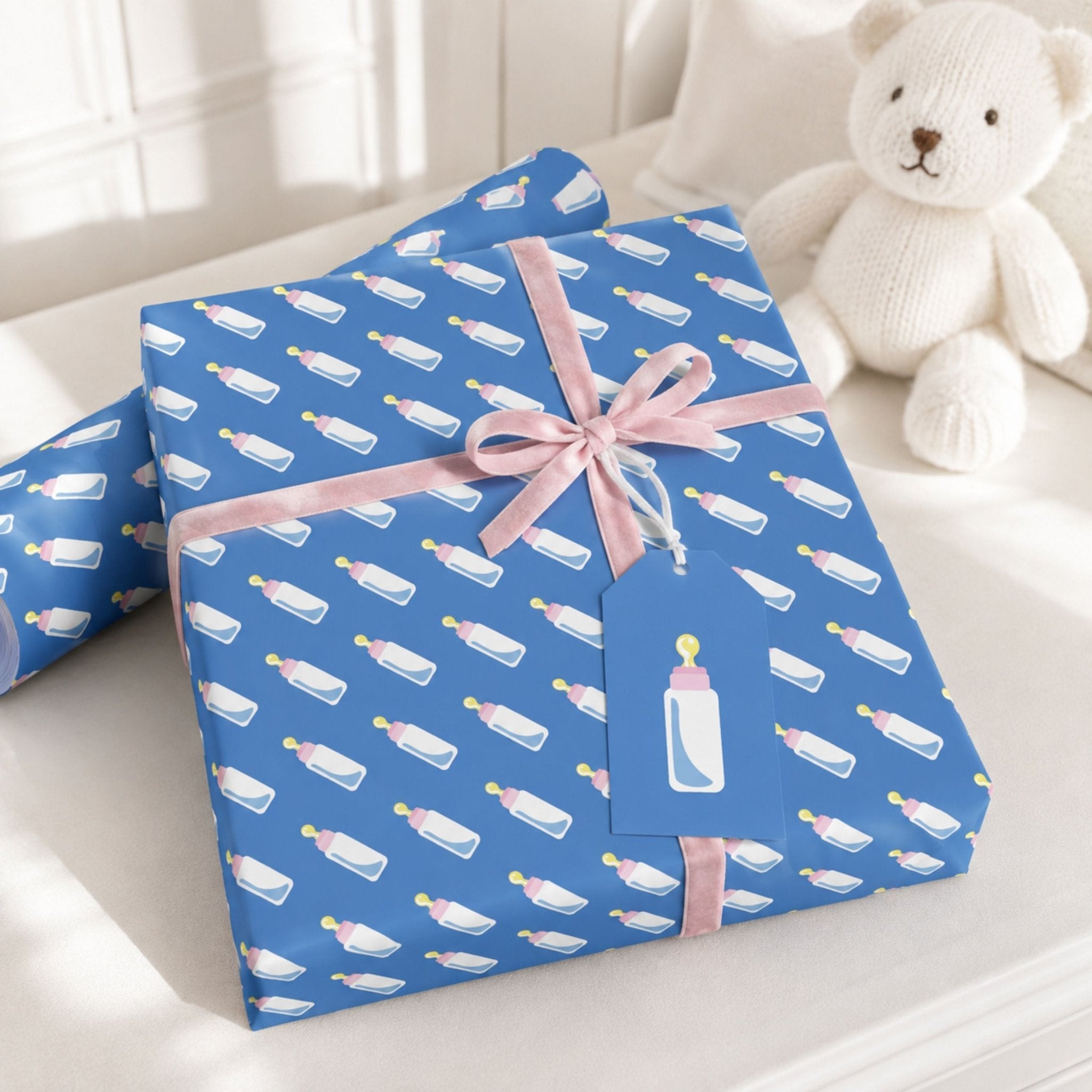 Blue baby bottle wrapping paper styled with pink ribbon for a new baby gift
