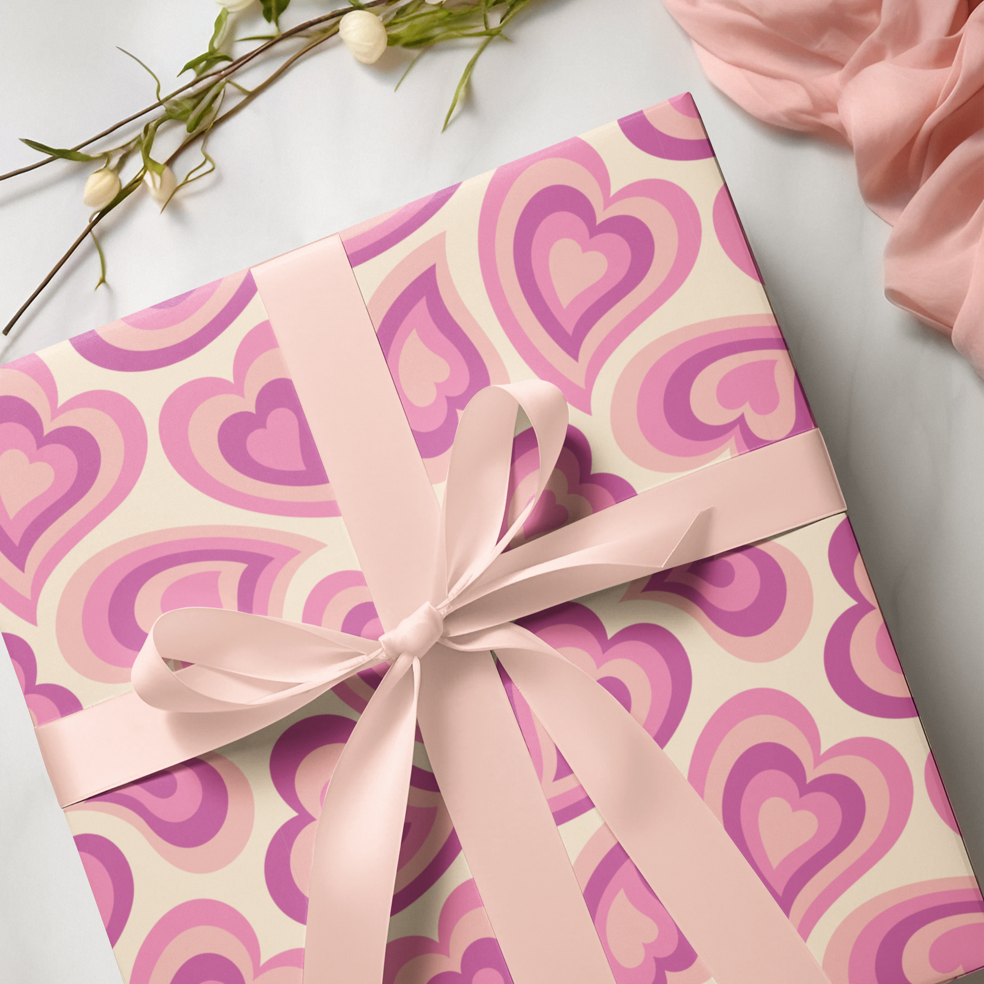 Gift box with pink heart pattern and pink ribbon on a light background