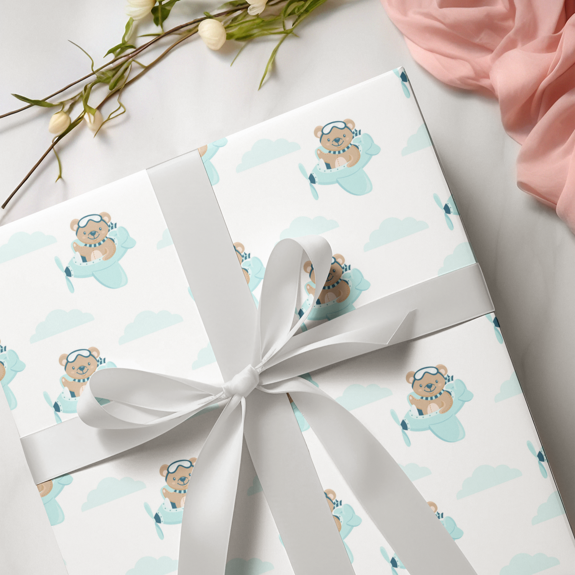 Gift wrapping paper with teddy bear design and white ribbon on a light background