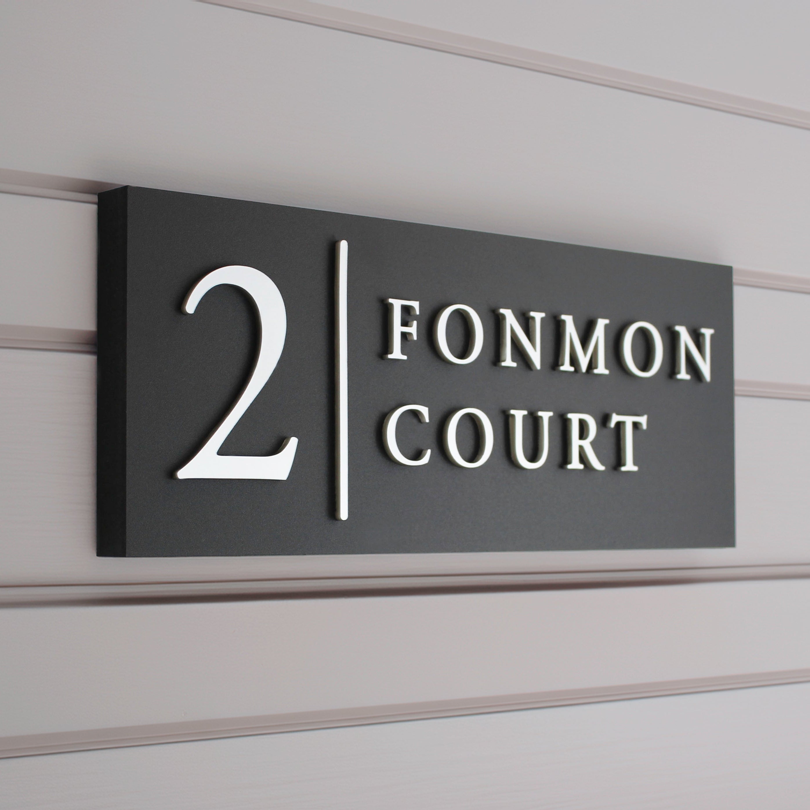 matte black house sign with raised silver design and vertical line