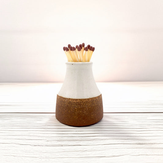 This ceramic milk bottle match striker comes filled with 20 safety matches and features a striker pad on the base. Hand-dipped in glaze, each piece has a unique finish, adding to its charm.

A stylish and practical addition to any candle-lit space, it’s designed for both convenience and display.

Handmade in small batches by skilled artisans in Southern India.

We also offer matchstick refills, so you can keep enjoying it time and time again.
this variant is a white match stick holder