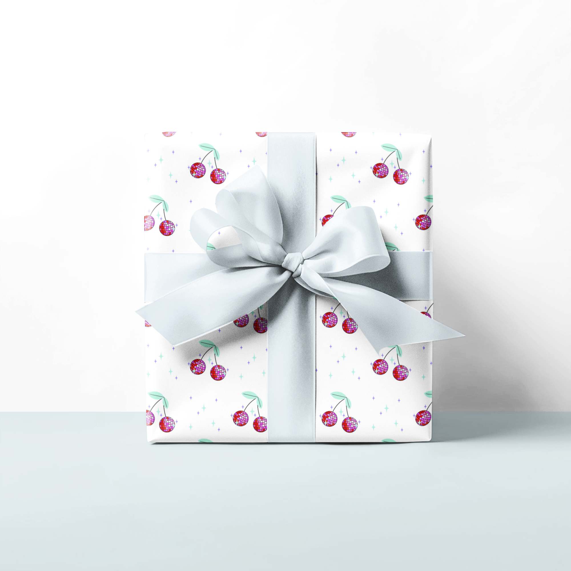 Gift box with cherry design and white ribbon on a light background