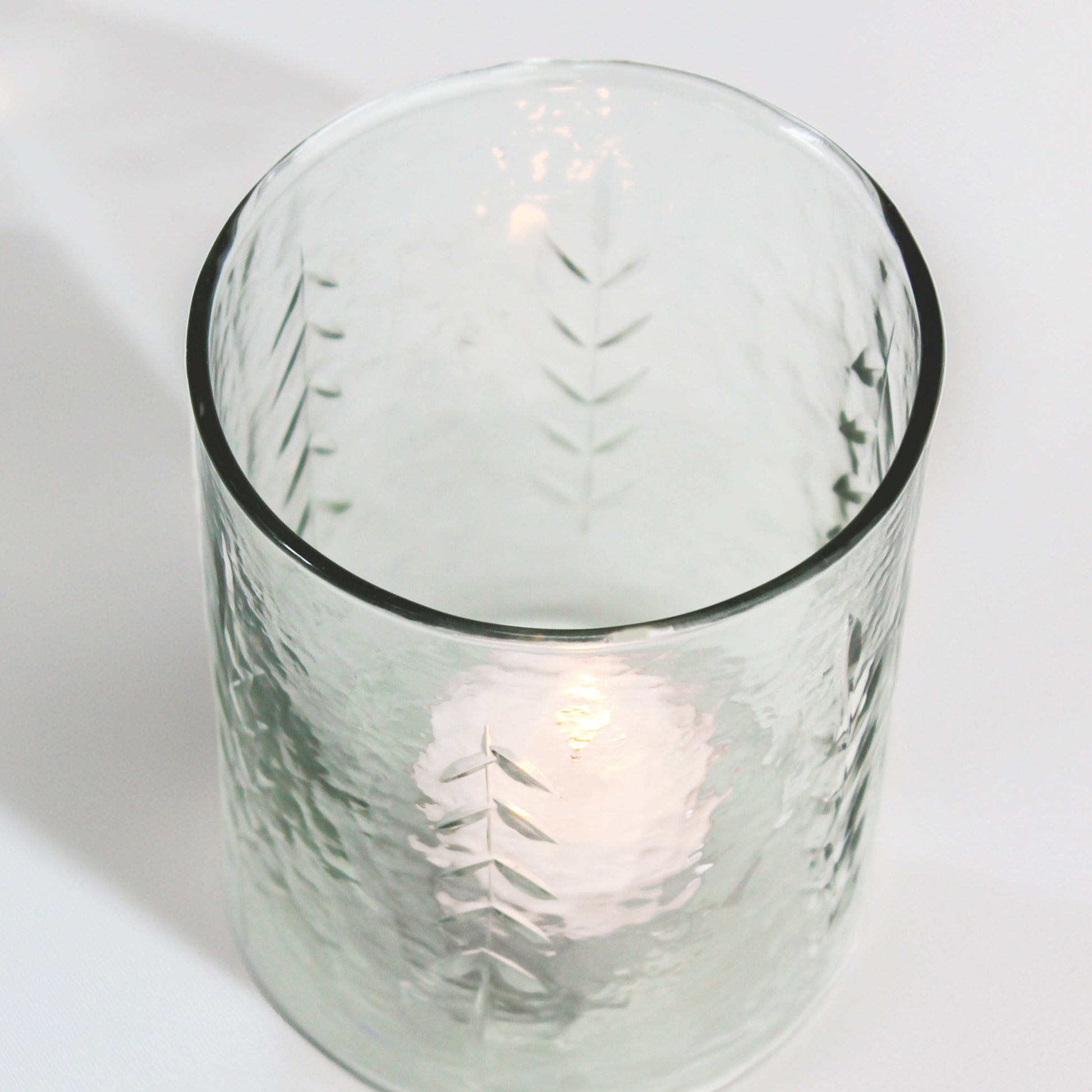 Clear glass candle holder with a candle inside on a white background