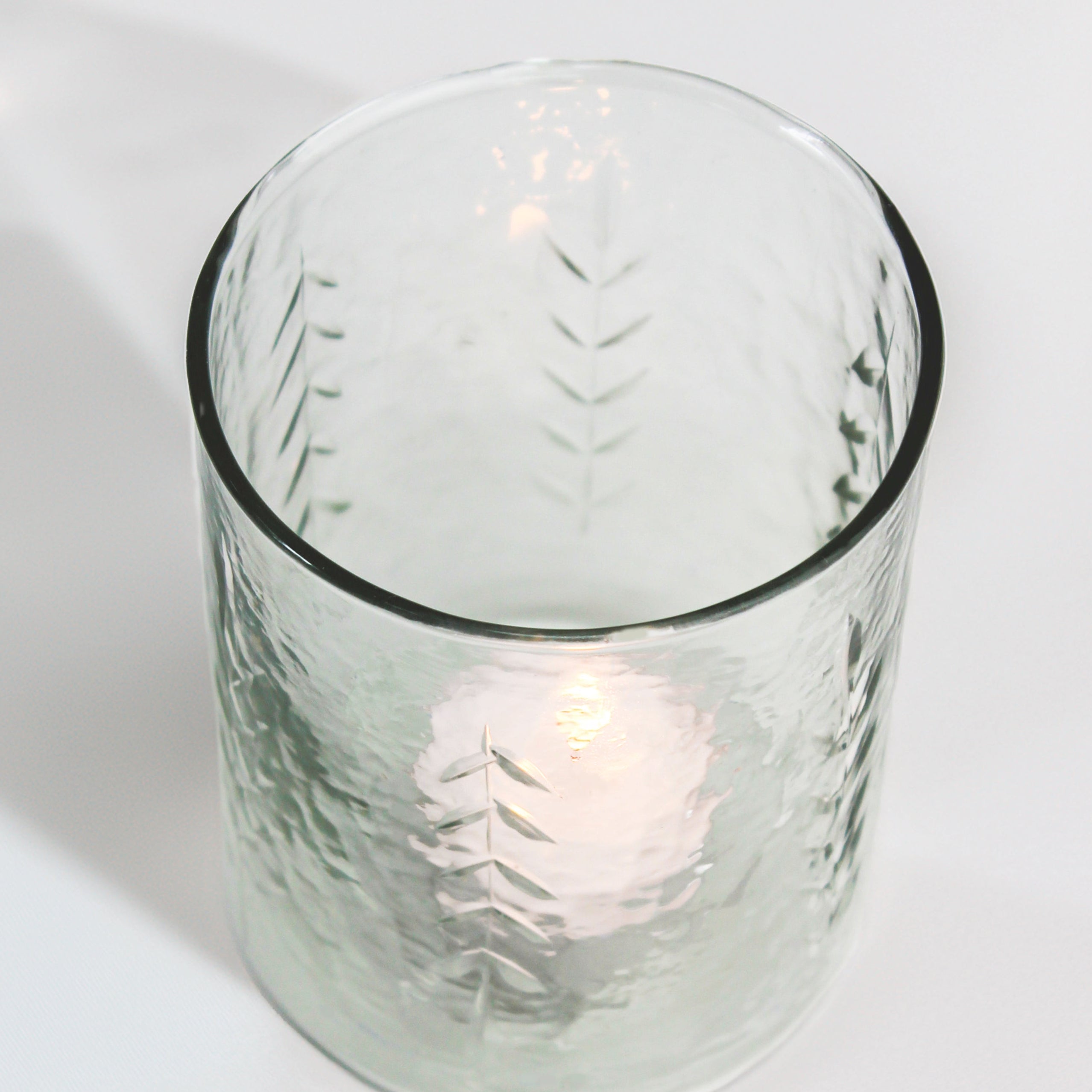Clear glass candle holder with a candle inside on a white background