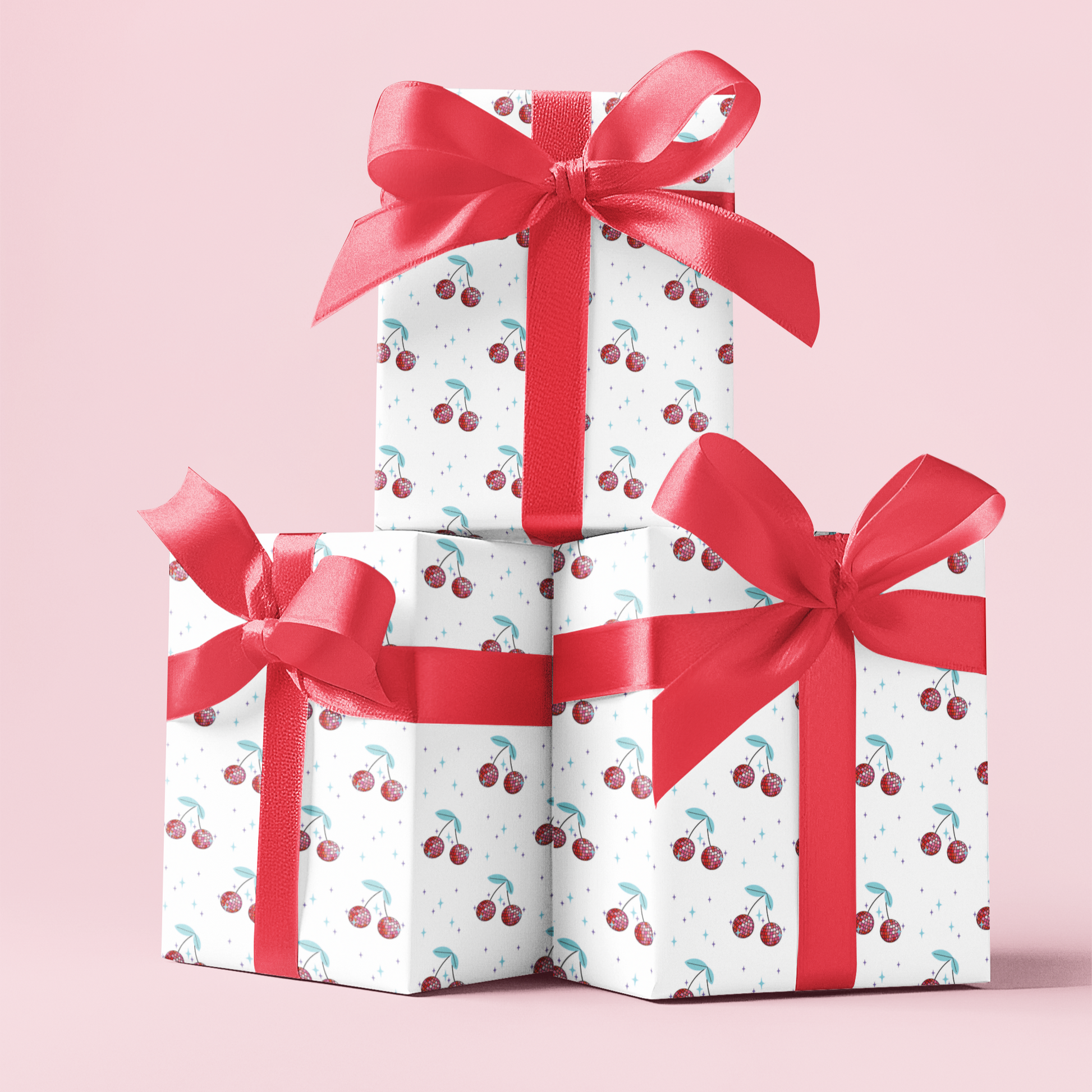 Three gift boxes wrapped with cherry disco balls pattern and red ribbons stacked on a pink background