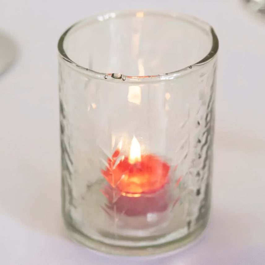 Clear glass candle holder with a small candle inside on a white surface