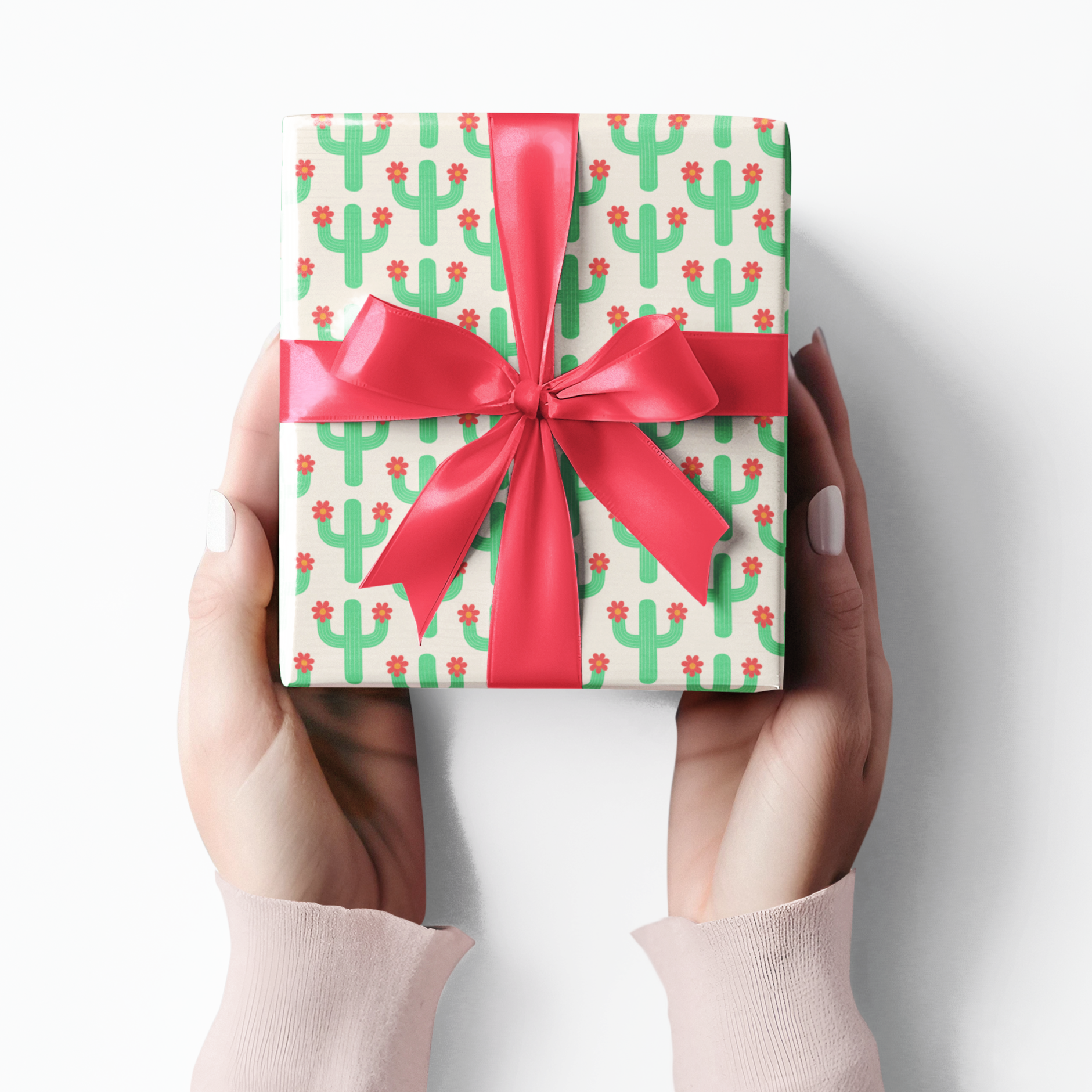 Gift box with cactus pattern and red ribbon held by hands on a white background