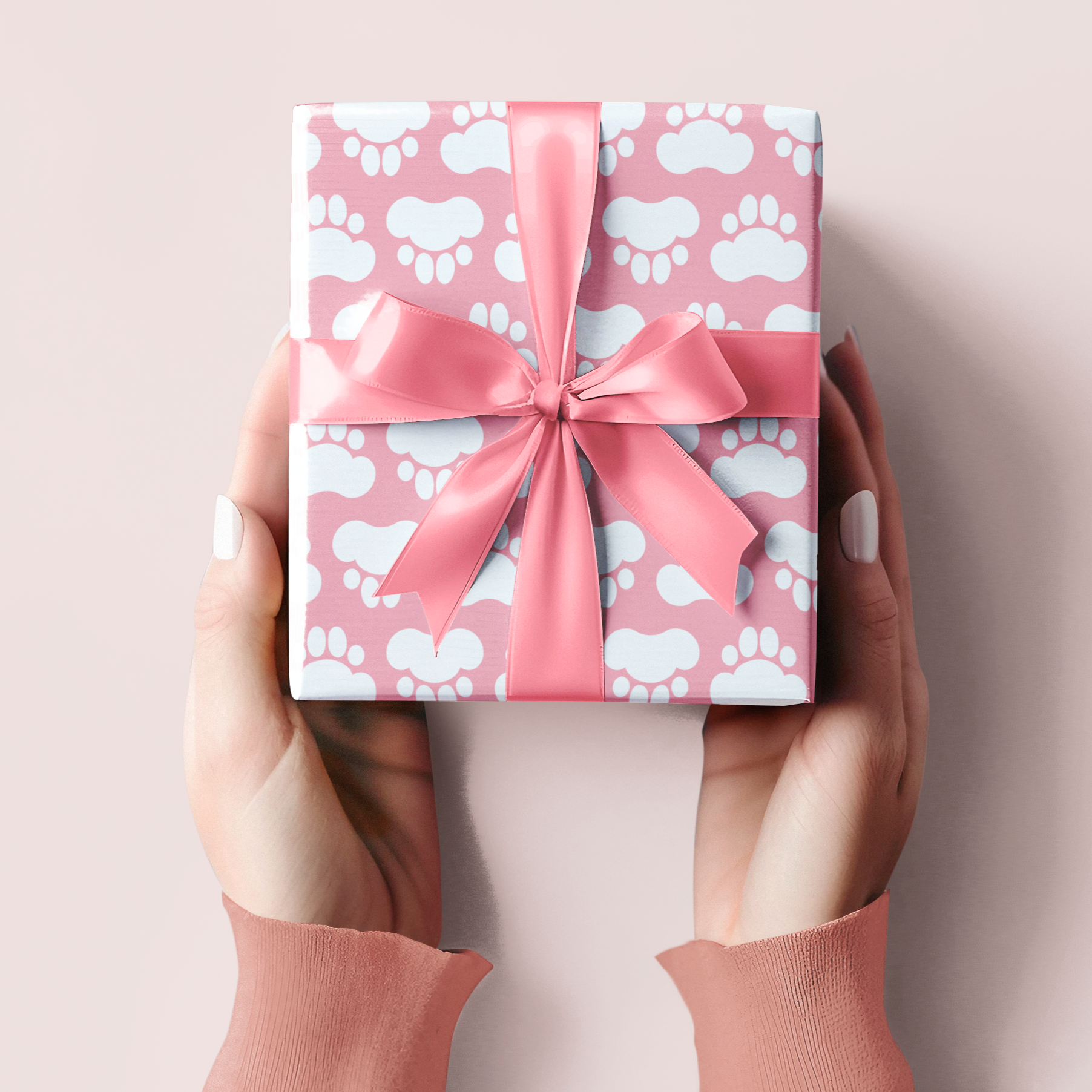 Pink gift box with a bow held by hands on a light pink background paw print design perfect for puppy gift