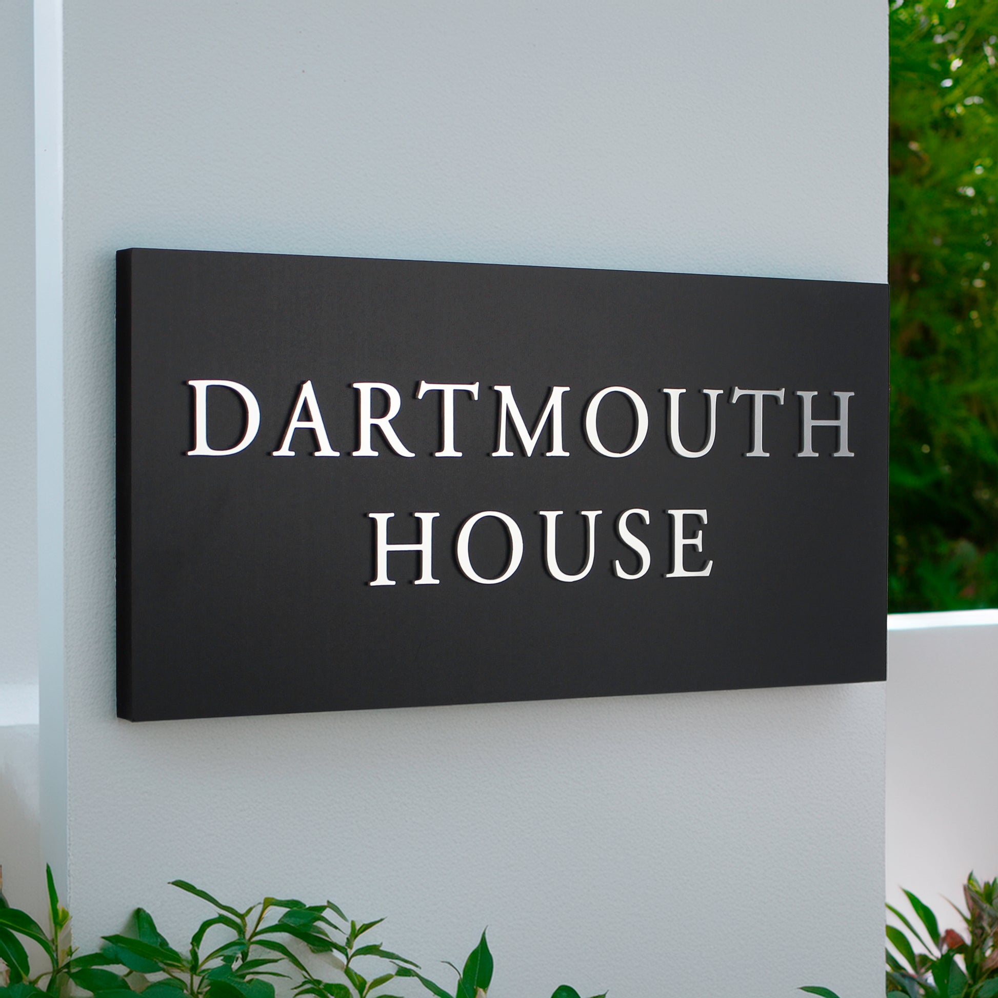 large matte black house sign with raised silver design text over 2 lines