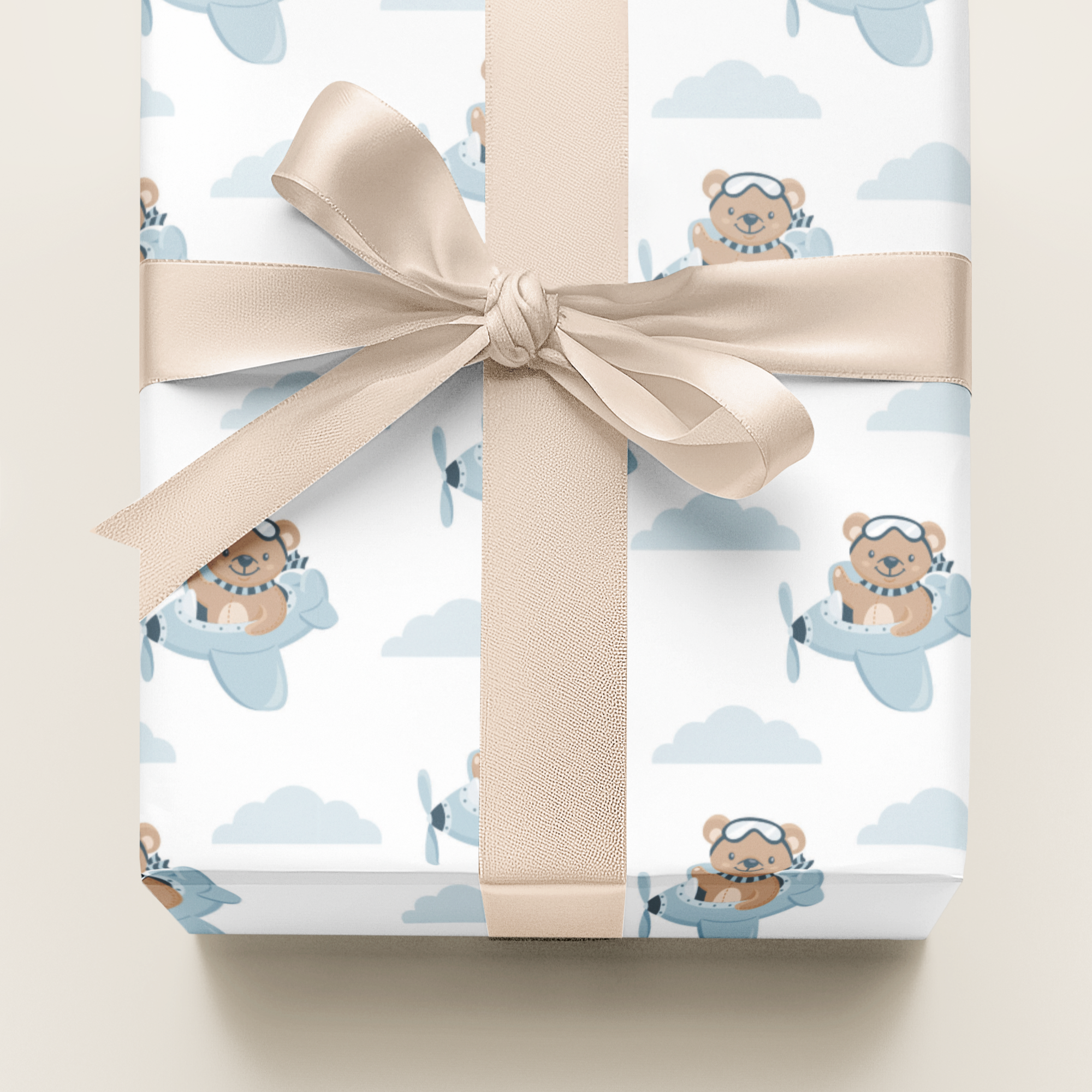 Gift wrapped in paper with teddy bear and airplane design, tied with a beige ribbon.
