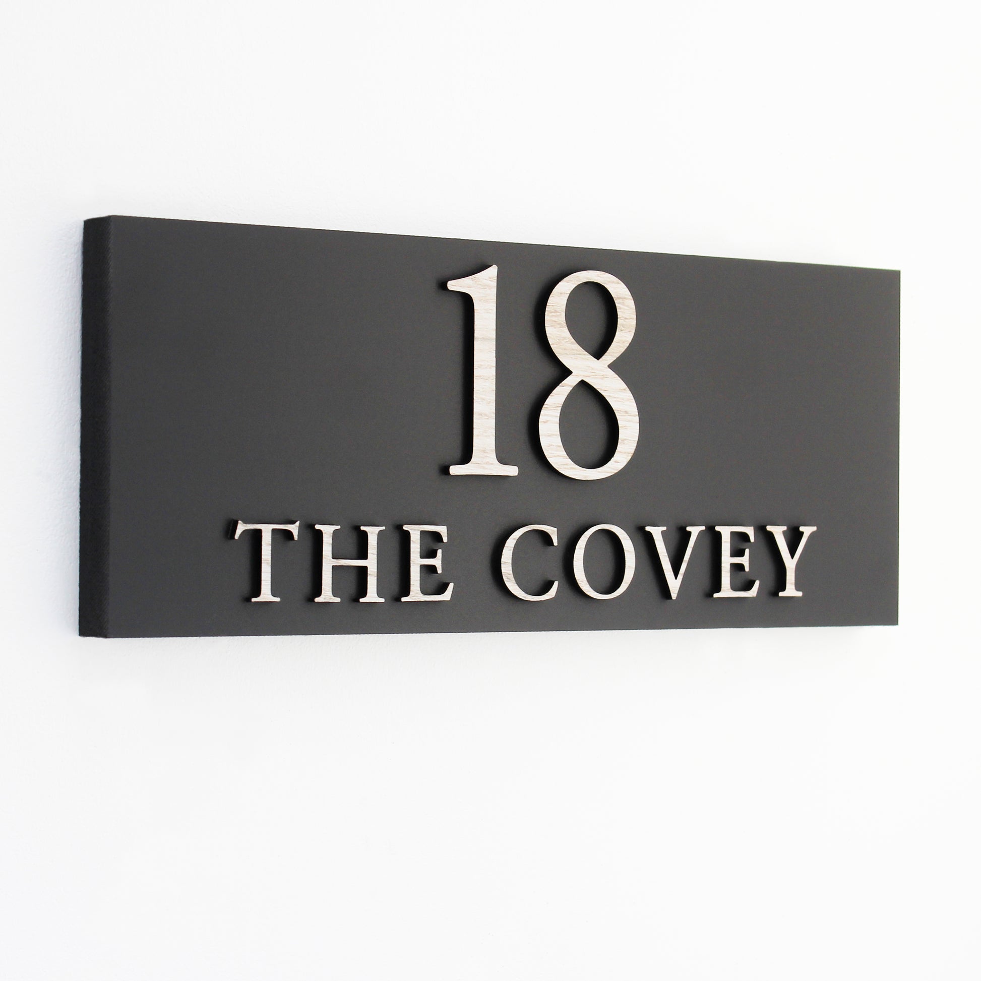 Black house number sign with number and wording in wood effect raised wording