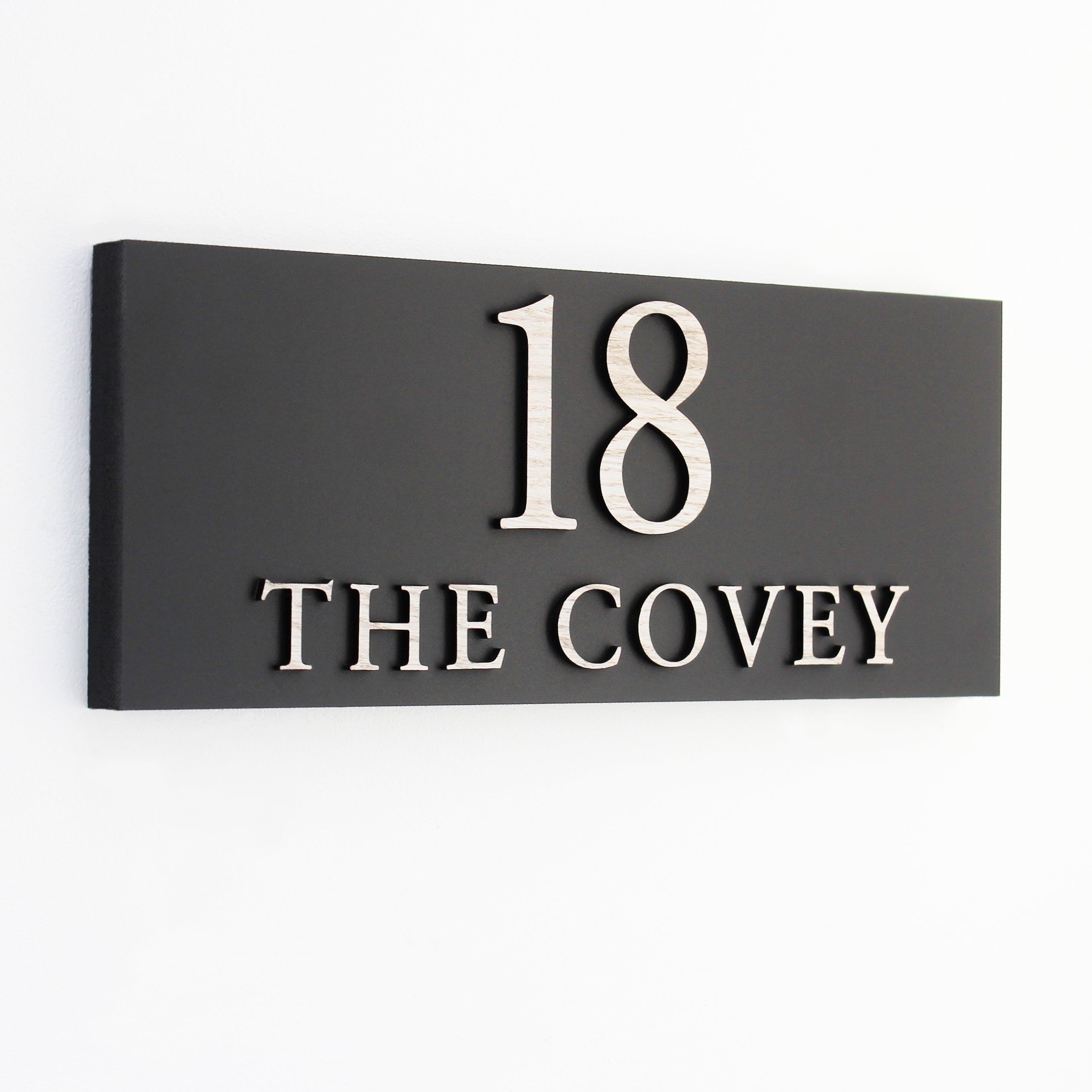 Black house number sign with number and wording in wood effect raised wording