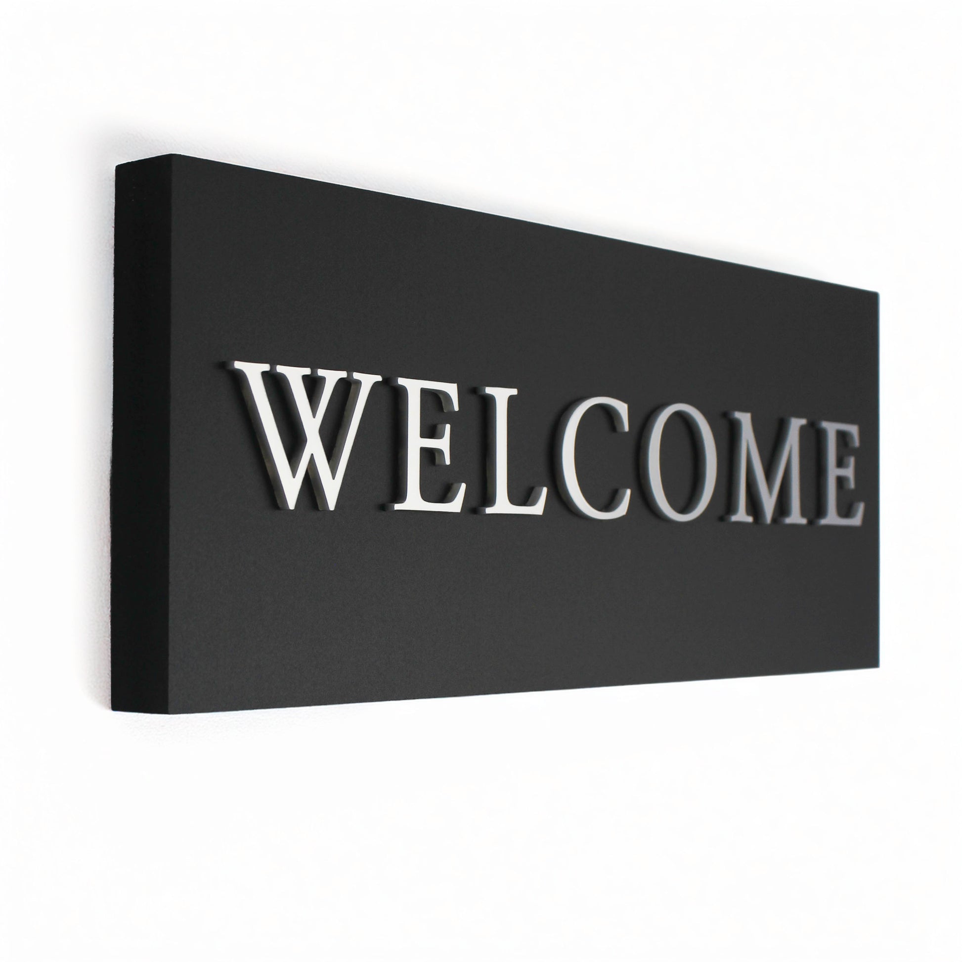 Black rectangular sign with 3D 'WELCOME' in silver letters on a black background