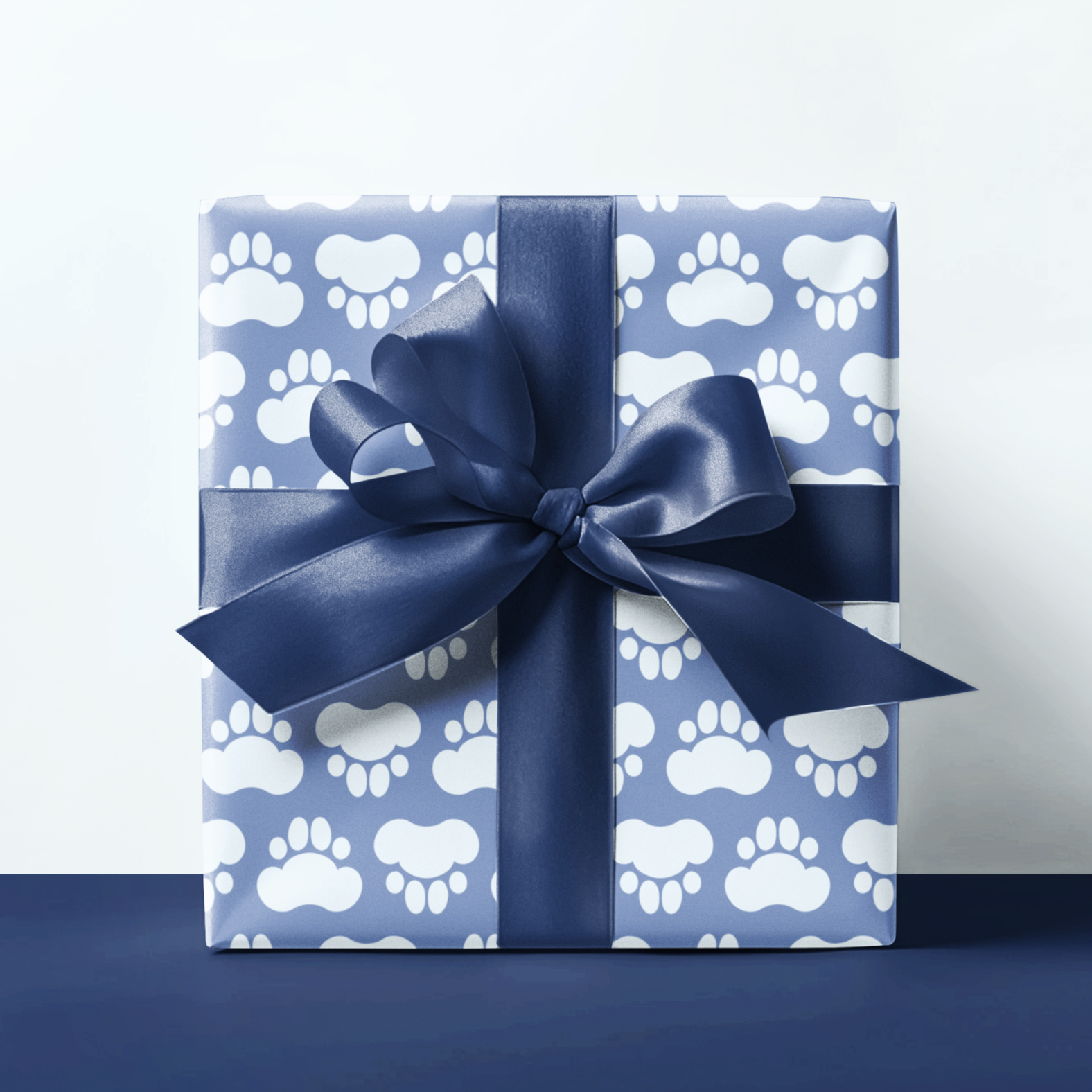 Gift box with paw print pattern and navy ribbon on a white background