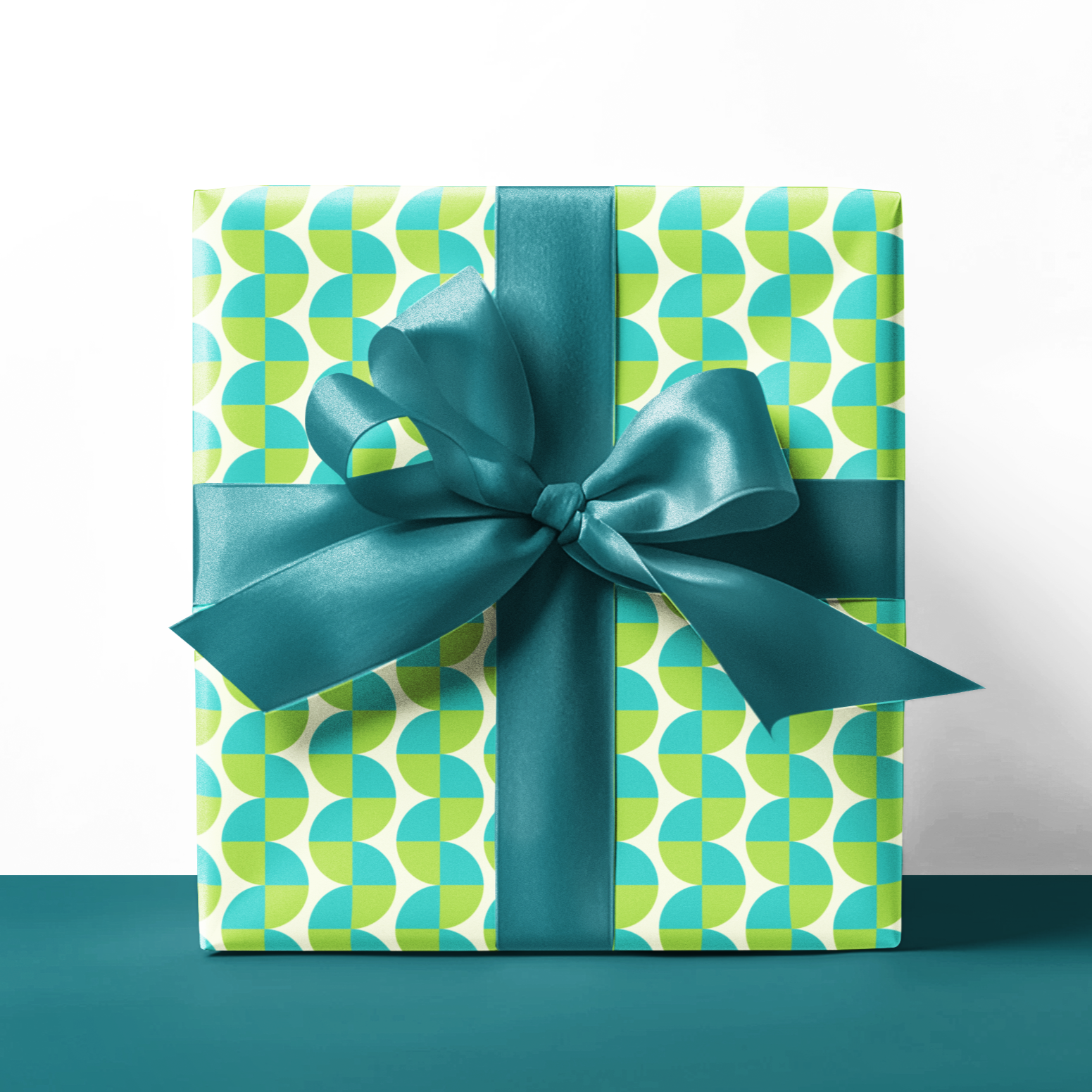 Gift box with green and blue pattern and bow on a white background