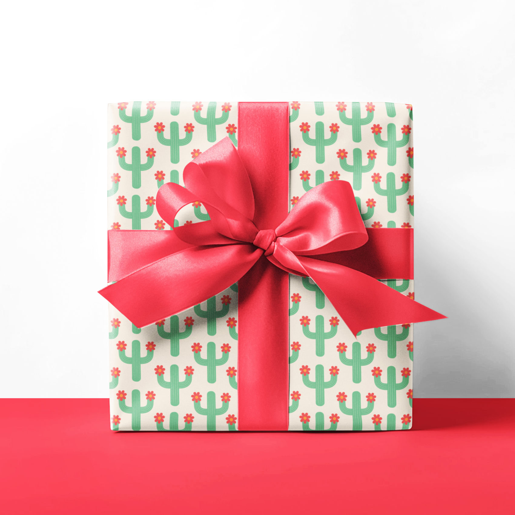 Gift wrap paper cactus design with a red bow on a white background