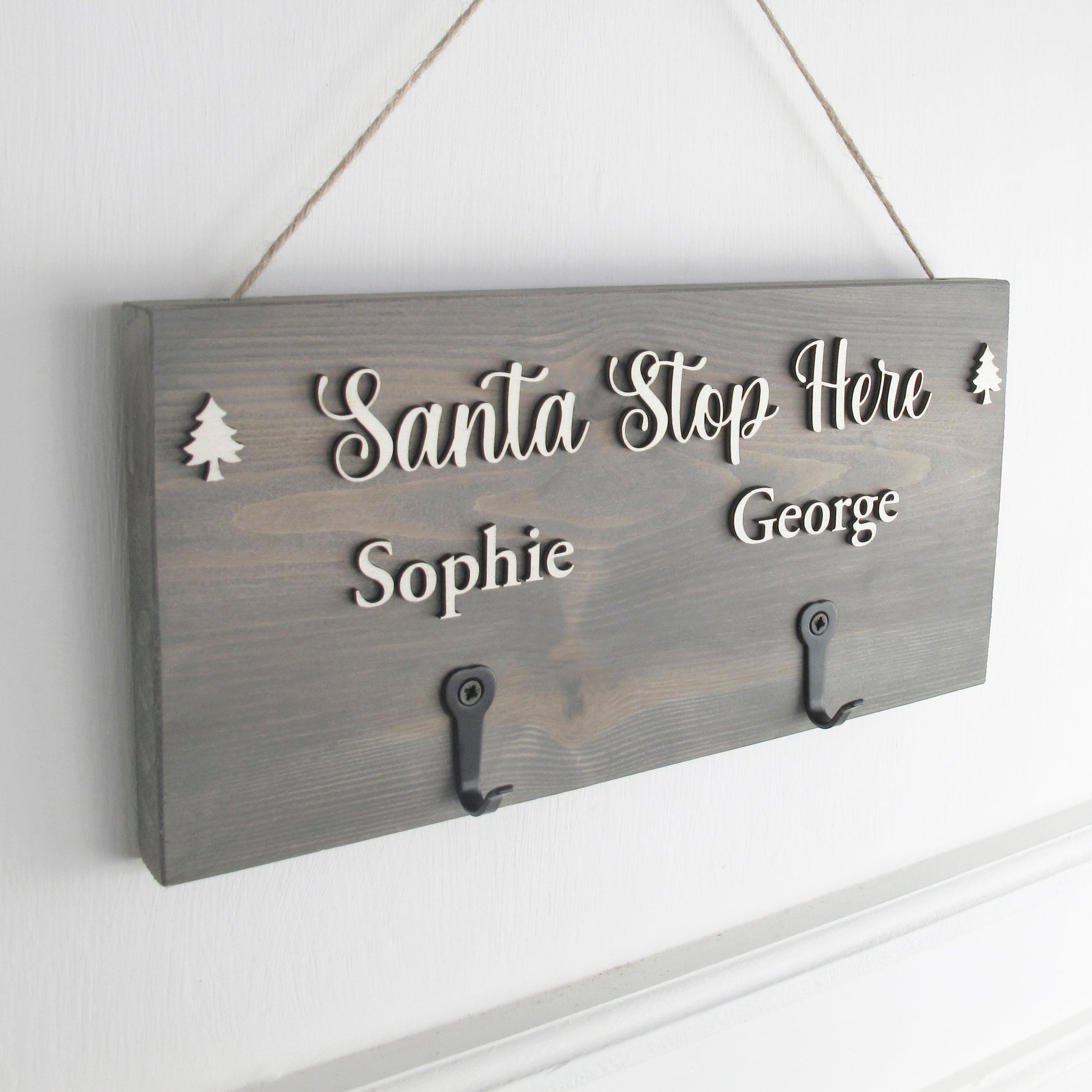 Wooden sign with 'Santa Stop Here' and names on a white wall