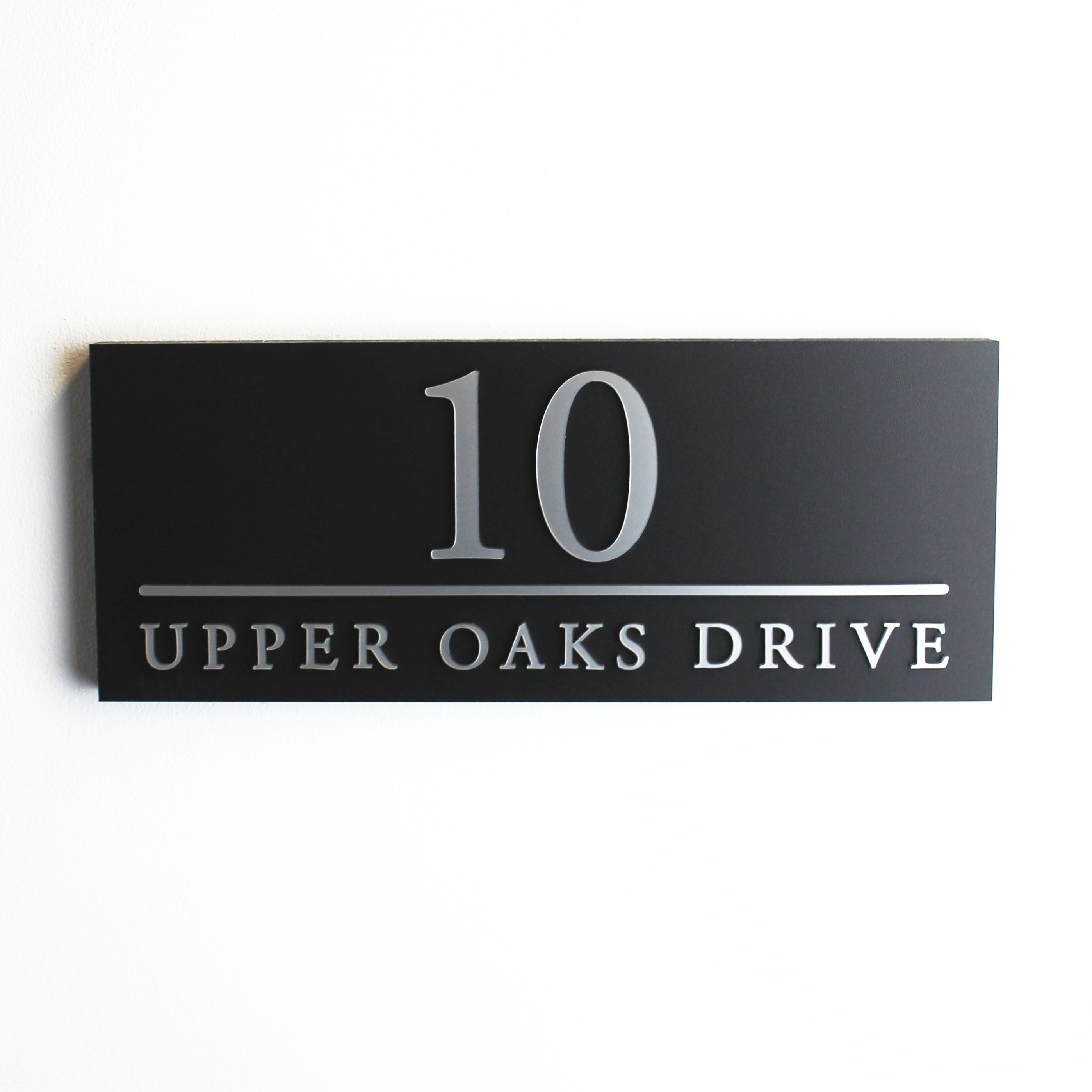Durable black house sign with a structured layout, ideal for displaying house numbers and street names.
