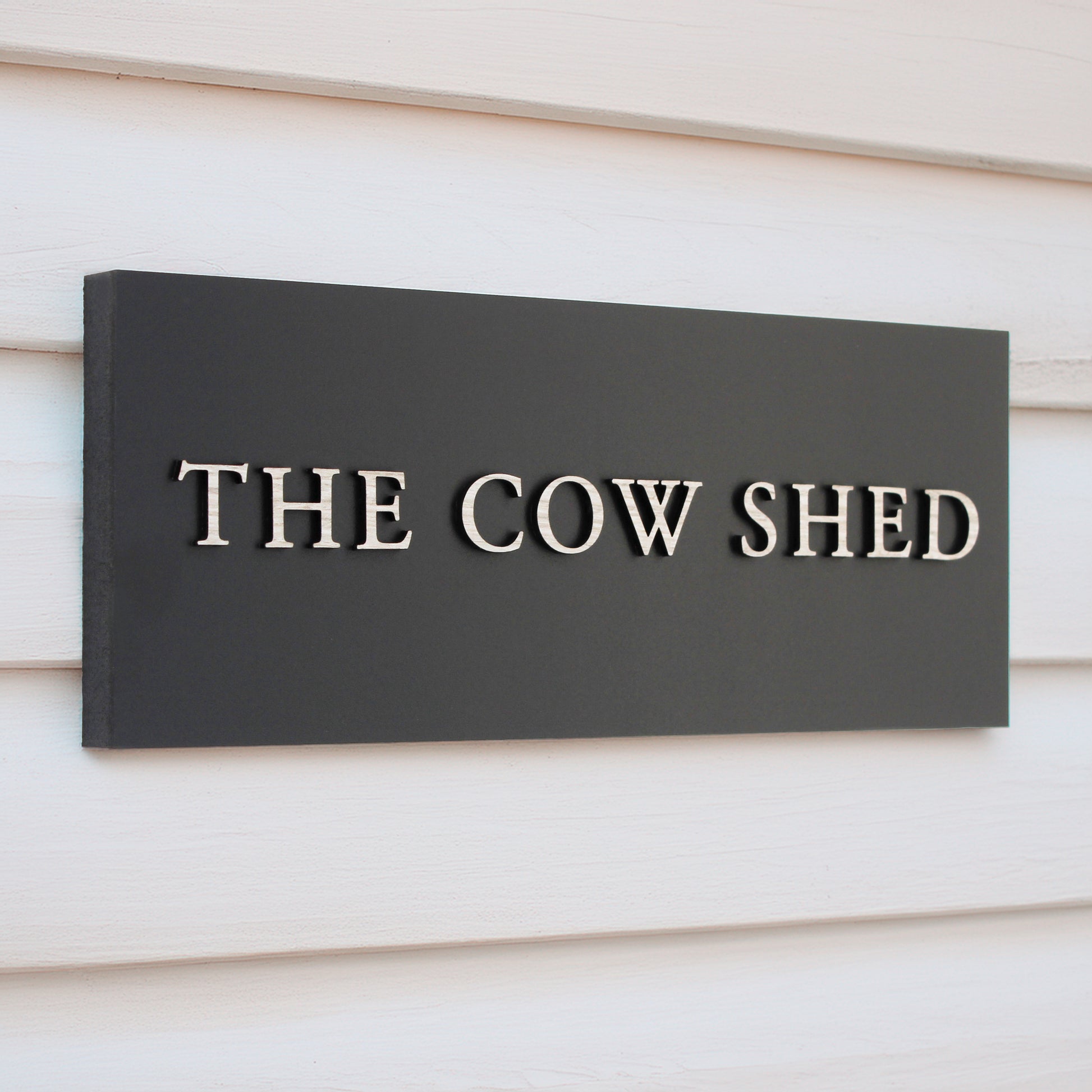 matte Black sign with one line of wording in raised wood effect