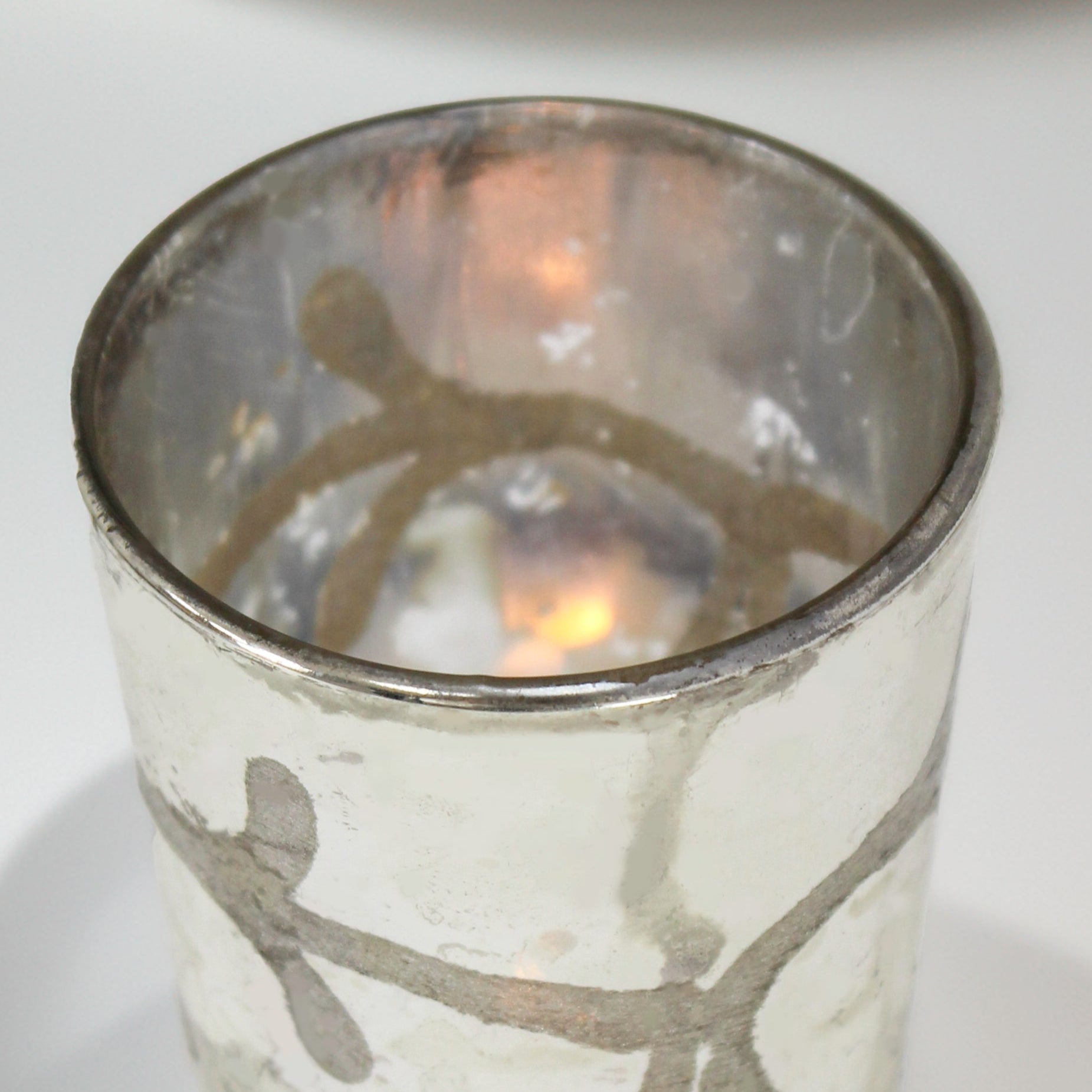 Silver candle holder with a candle inside on a white background
