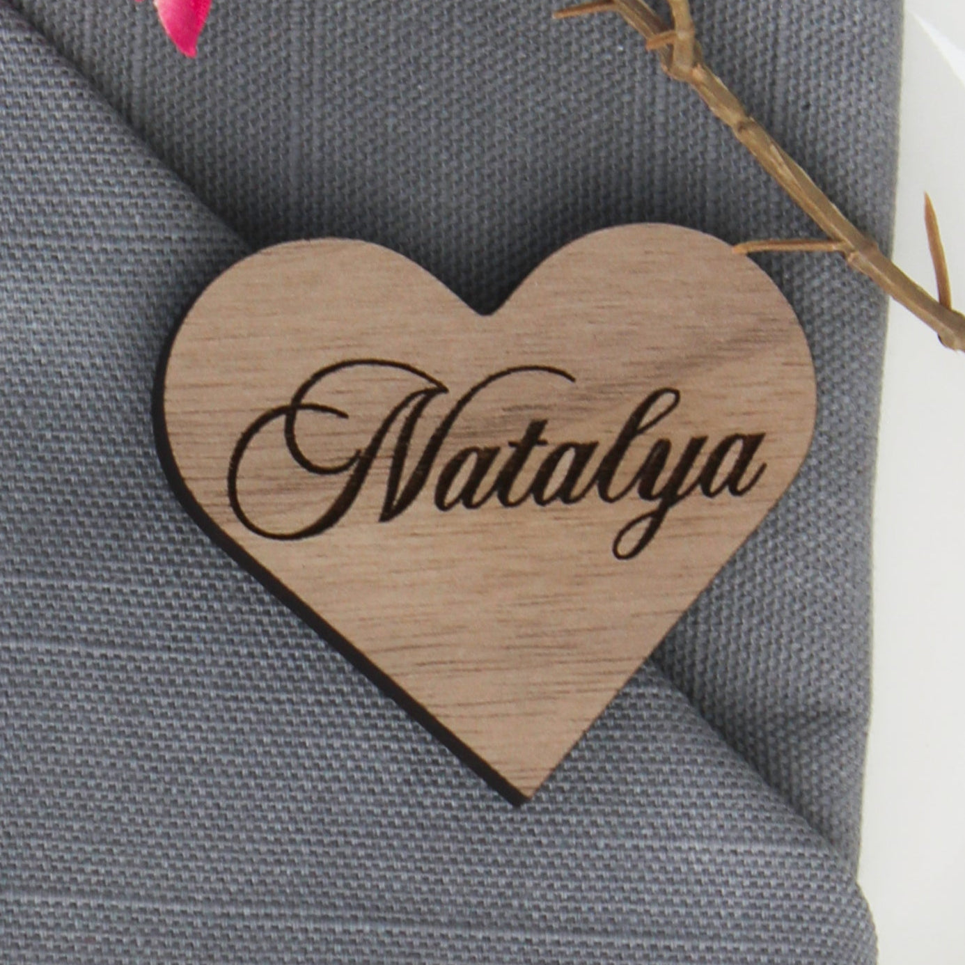 Heart-shaped name tag with 'Natalya' on a gray napkin with floral decoration.