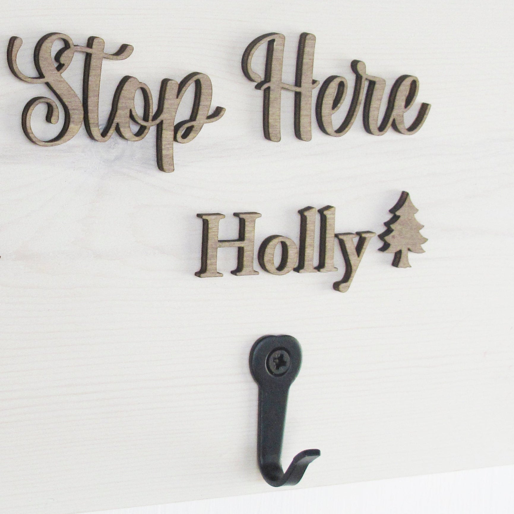 Decorative sign with 'Santa Stop Here' text and hooks on a white background