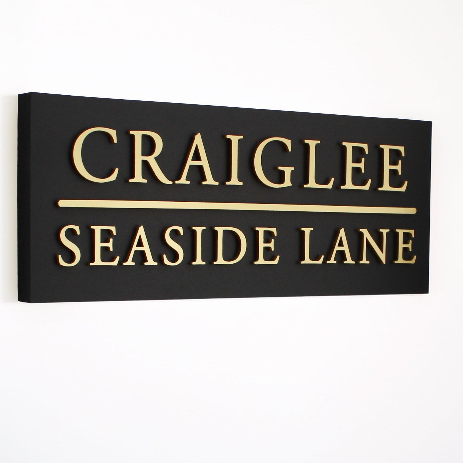 matte black very large house sign with gold wording and a dividing line 