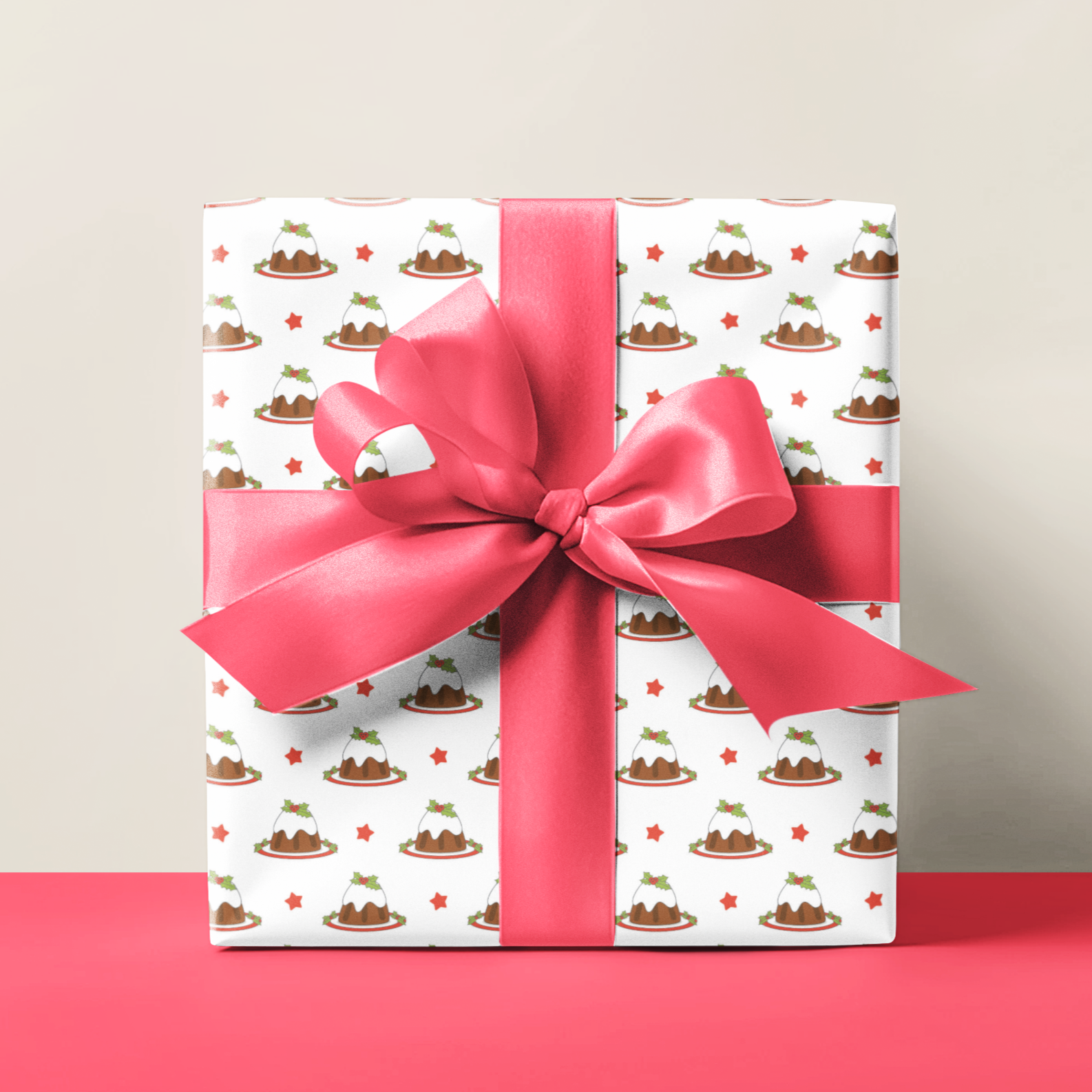 Christmas pudding gift wrap with a pink ribbon on a red surface and beige background
