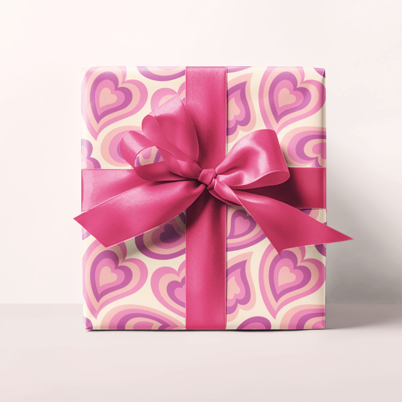 Gift box with pink heart pattern and bow on a white background
