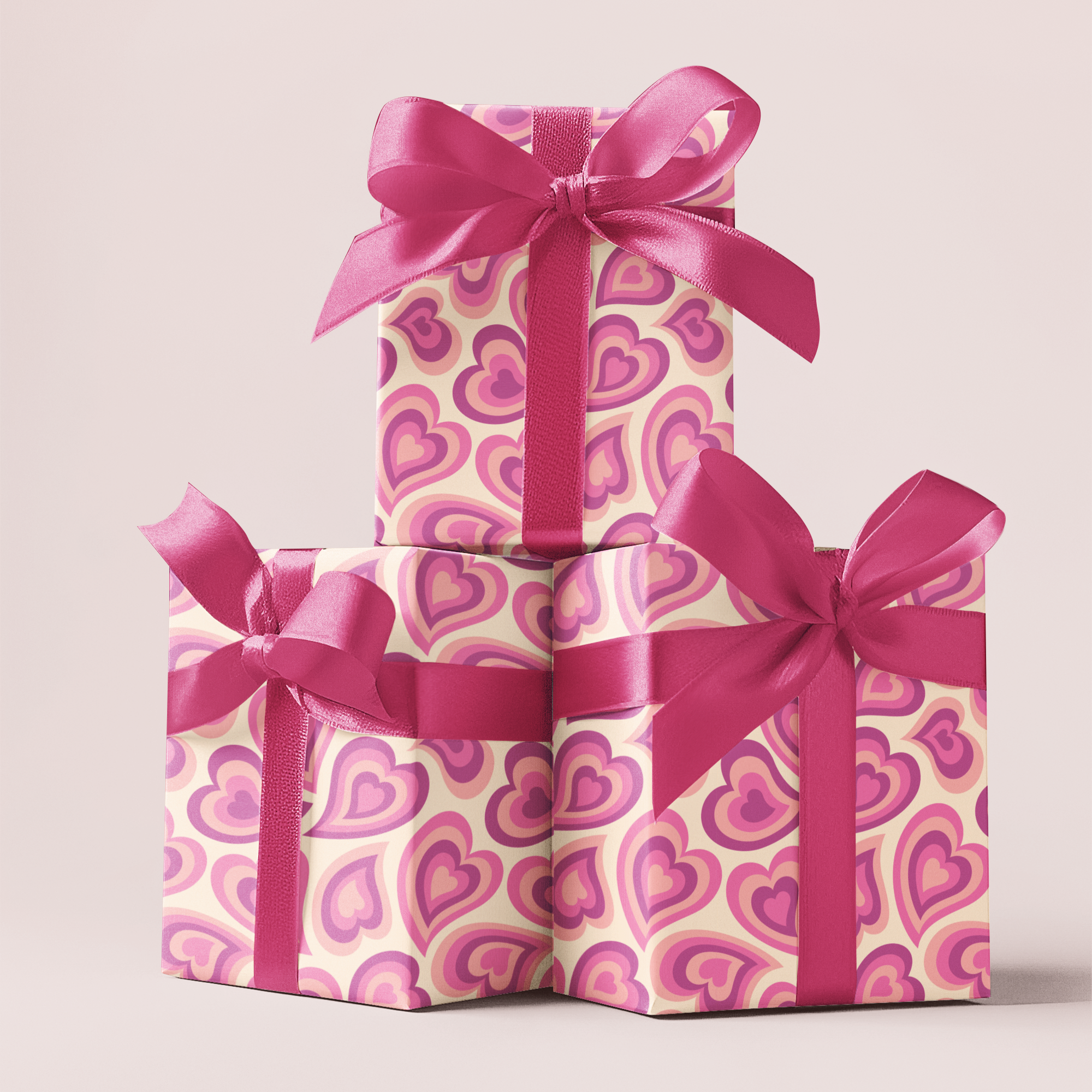 Three stacked gift boxes with heart patterns and pink ribbons on a light background